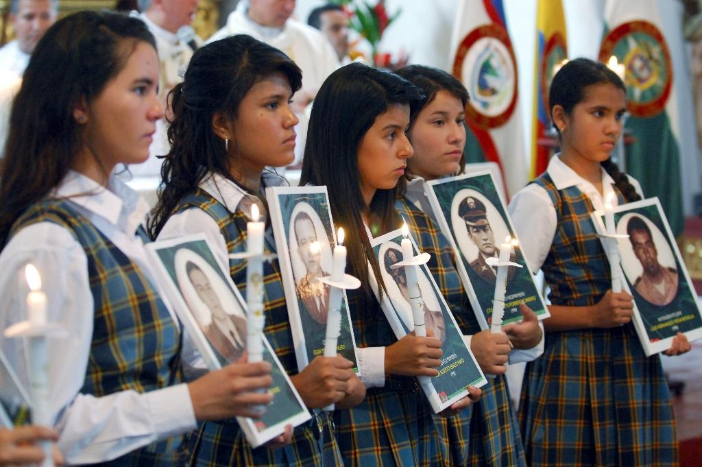 Studenter bär ljus och fotografier av poliser som kidnappats i Colombia. (Foto: Carlos Julio Martinez/AP/TT)