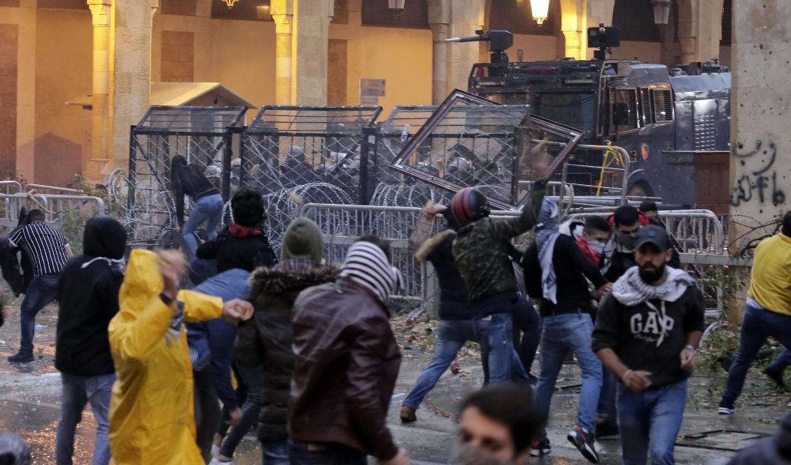 
Demonstranter drabbar samman med kravallpolis vid en av vägarna som leder fram till Libanons parlament i Beirut. Foto: Hassan Ammar/AP/TT                                                