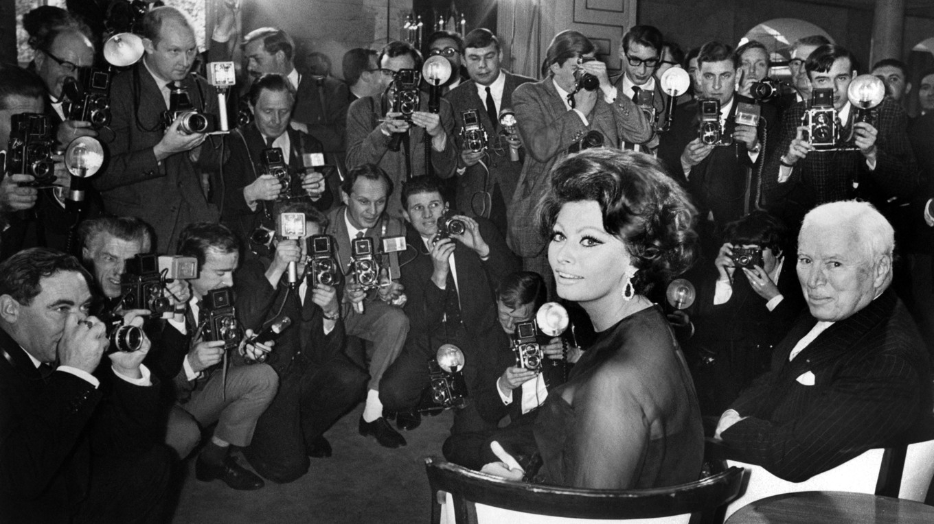 Presskonferens den 1 november 1965 på Savoy Hotel i London för filmen ”Grevinnan från Hongkong”. Filmen, som hade urpremiär den 5 januari 1967 i Storbritannien, regisserades av Charlie Chaplin som även skrev manus och soundtrack. I filmen, som kom att bli mästerregissörens sista, spelar Sophia Loren och Marlon Brando huvudrollerna.
För Loren var det en dröm som gick i uppfyllelse att få arbeta med legendaren Chaplin. ”Jag hade kunnat recitera telefonkatalogen bara för att få arbeta med honom. Jag var så nervös inför att få jobba med honom, men under den första inspelningsdagen insåg jag att han var lika nervös.” 
Av Chaplin fick Loren rådet att lära sig att säga nej till saker. ”Annars kommer du bara att leva ditt liv för att tillfredsställa andra, och du kommer aldrig att bli nöjd med dig själv.” Sophia Loren säger att Chaplins råd är det bästa hon någonsin har fått. 
Skådespelerskan Tippi Hedren (född 1930) medverkade även hon i filmen, och berättade i en intervju om inspelningen att ”Regissörer har olika sätt att arbeta. Chaplins sätt var att själv visa hur han ville att skådespelarna skulle agera. Men han gjorde inte det genom att regissera. Han gjorde det genom att säga ’Ok, gör så här’ och sedan själv spela upp allas roller. Han ’blev’ Sophia Loren, han ’blev’ Marlon Brando. Det var verkligen ett annorlunda tillvägagångssätt som jag aldrig tidigare hade sett. Jag tyckte att det var roande och charmigt, men du kan ju tänka dig hur Marlon Brando reagerade när någon sa åt honom hur han skulle agera. Han blev så förnärmad att han ville hoppa av, men Chaplin övertalade honom att stanna kvar. Sophia var rolig och charmig och vi blev goda vänner. En gång besökte hon mitt reservat Shambala i Kalifornien där jag har vilda djur. Jag visade henne lejonen, tigrarna och elefanterna. Sophia tappade under besöket bort sin anteckningsbok där alla hennes möten och telefonnummer stod inskrivna. När en anställd öppnade gapet på en av elefanterna så låg där det enda som var kvar av anteckningsboken, spiralbindningen, som nu var förvandlad till en stålklump.” Foto: Central Press/AFP via Getty Images