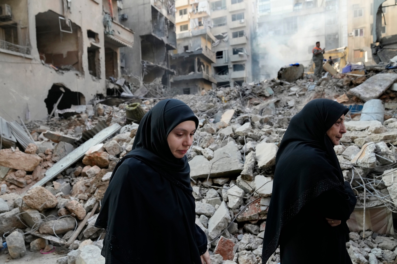 Libanesiskor går förbi de bombade byggnaderna i Beirut på fredagsmorgonen. Foto: Hussain Malla/AP/TT