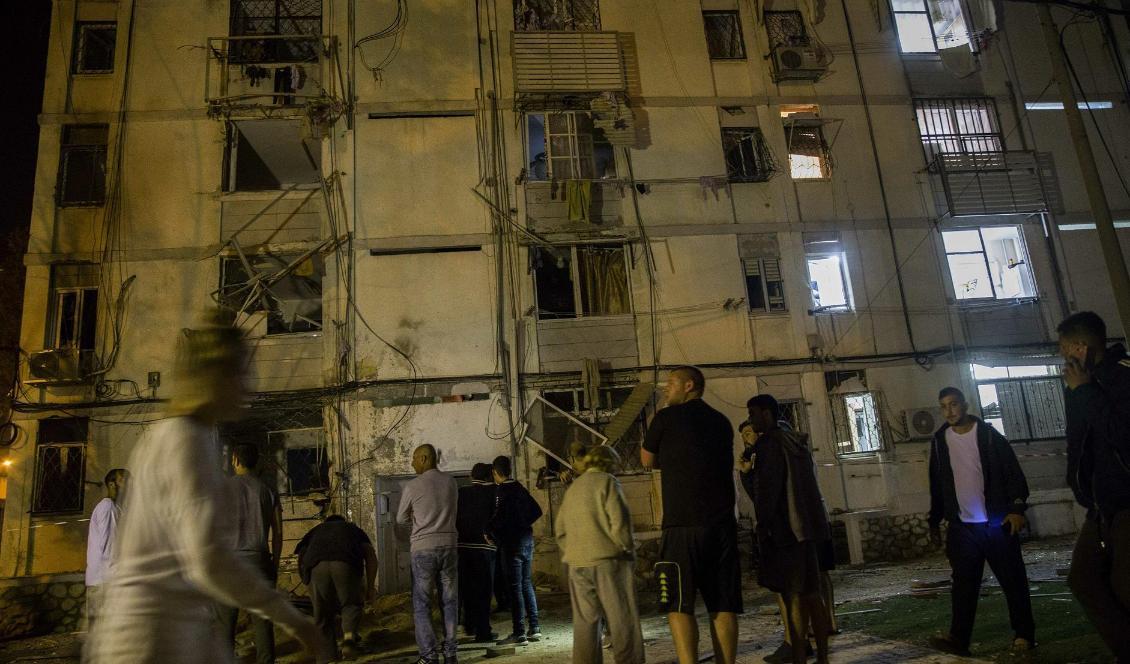 Israeler utanför ett bostadshus som under natten träffats av raketer. Foto: Tsafrir Abayov/AP/TT