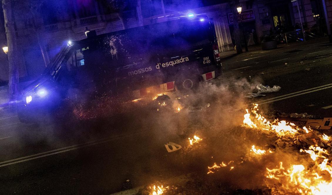 En polisbil kör över brinnande barrikader i Barcelona under natten till fredagen. Foto: Bernat Armangue/AP/TT