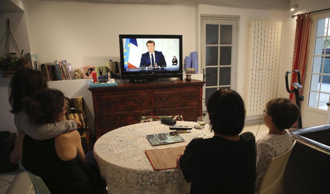 En familj lyssnar till Emmanuel Macrons tal. Foto: Bob Edme/AP/TT