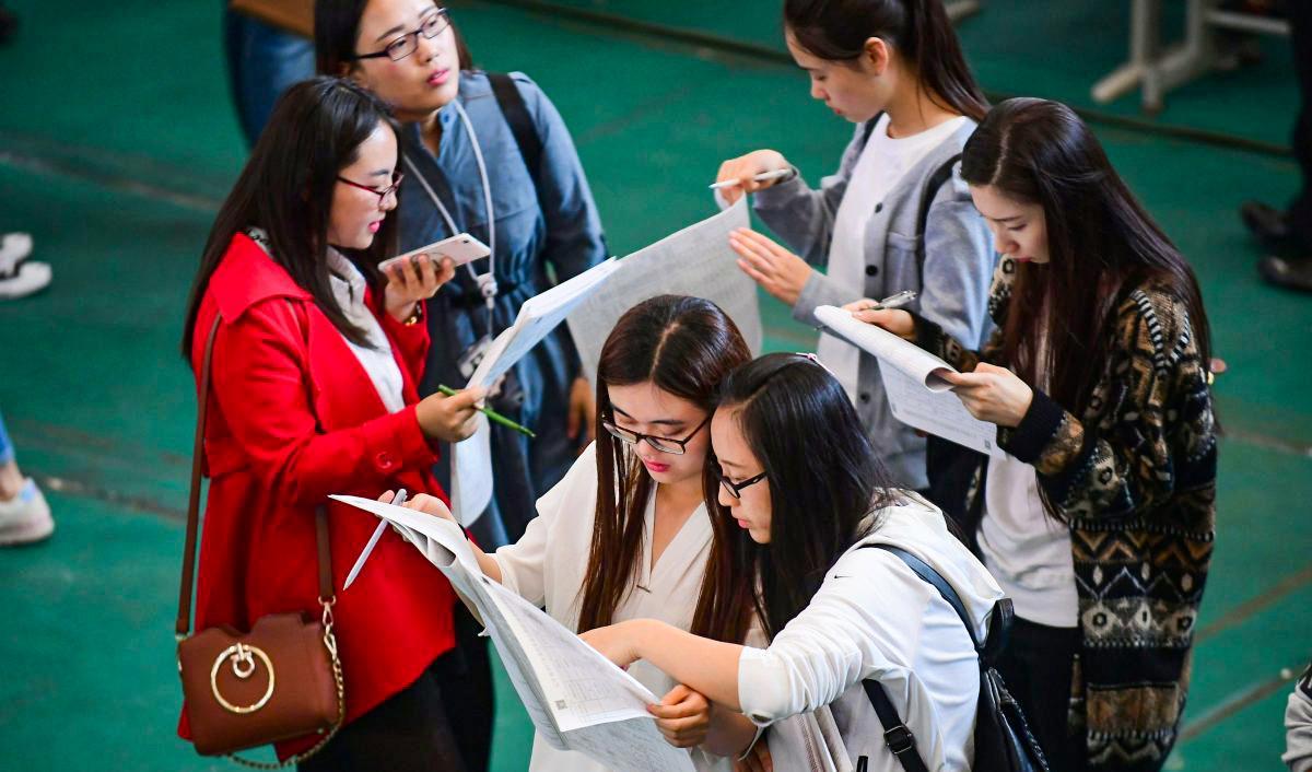 Unga vuxna läser platsannonser under en jobbmässa på Shenyang Aerospace University i Shenyang, Liaoning provinsen, den 13 maj 2017. Foto: STR/AFP via Getty Images