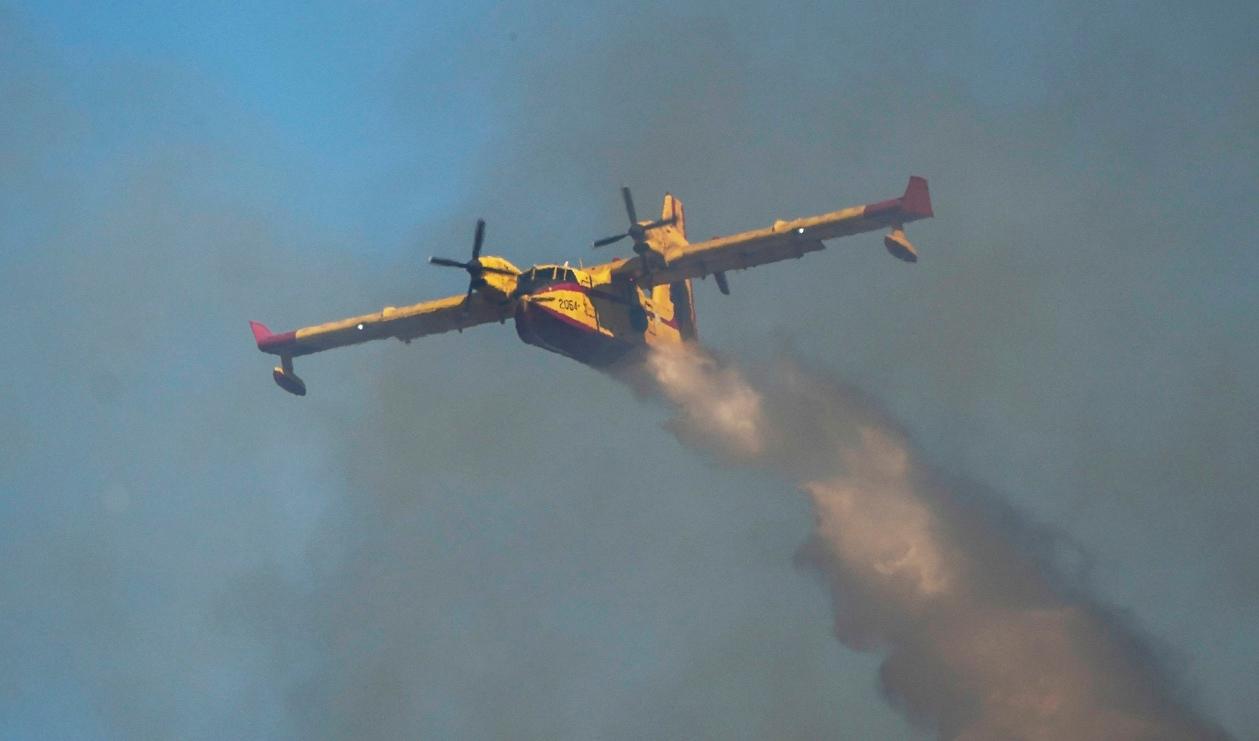 Ett vattenbombande flygplan bekämpar bränder över Rhodos under tisdagen. Planet på bilden är inte det som har störtat. Foto: Petros Giannakouris/AP/TT