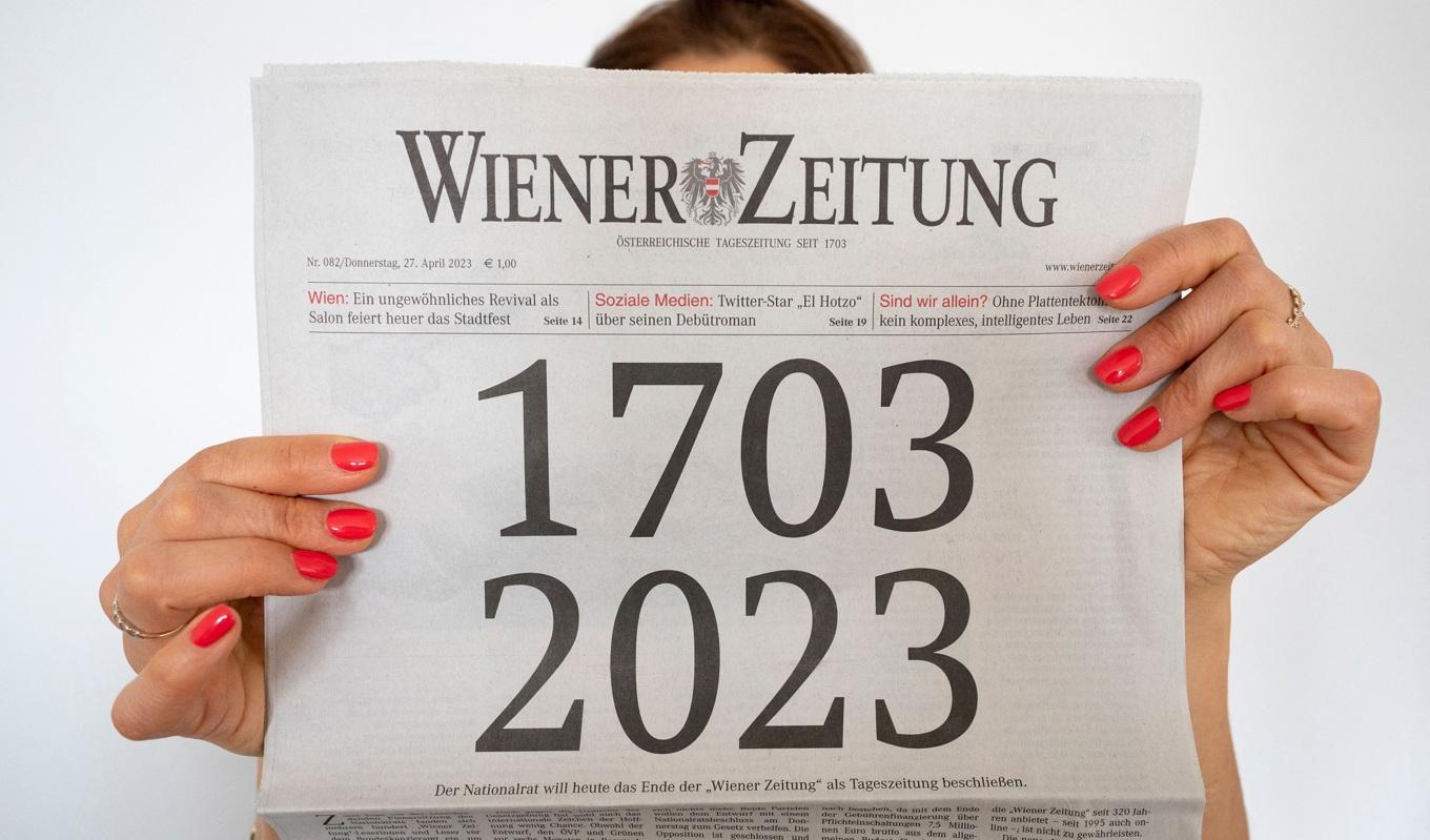 En kvinna håller upp österrikiska Wiener Zeitung som har funnits i 320 år och är en de äldsta tidningarna i världen. Foto: Joe Klamar/AFP via Getty Images