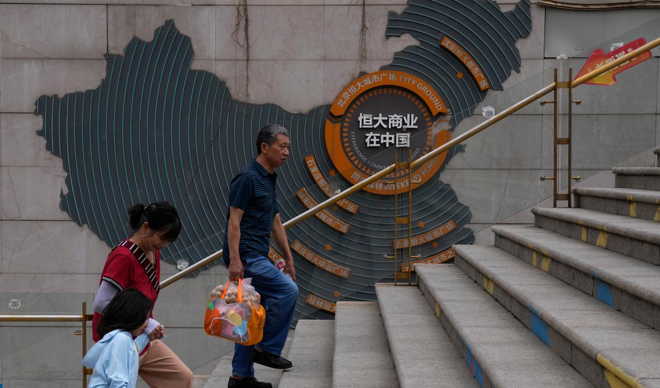 Boende går förbi en karta som visar Evergrandes fastighetsprojekt i Kina. Arkivbild. Foto: Andy Wong/AP/TT