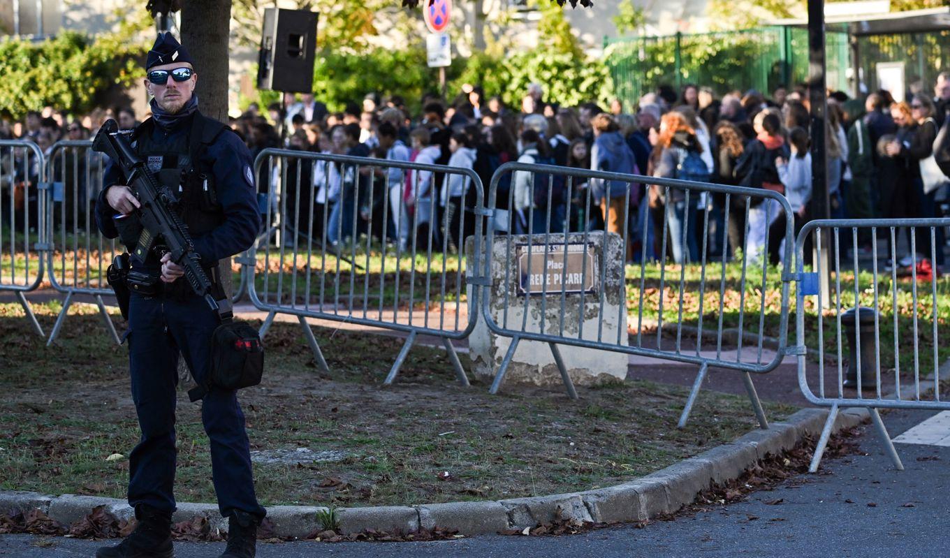 På bilden ses en fransk polis i samband med en tyst minut för de mördade lärarna Samuel Paty och Dominique Bernard framför Bois d'Aulne-skolan i Conflans-Sainte-Honorine utanför Paris den 16 oktober 2023. Foto: Bertrand Guay/AFP via Getty Images