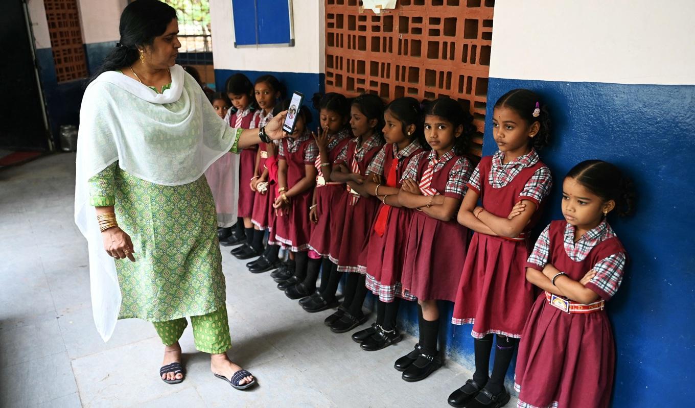 En lärare fotograferar elever med en ansiktsigenkännings-applikation på en statlig grundskola i Hyderabad, den 9 november. Foto: Noah Seelam/AFP via Getty Images