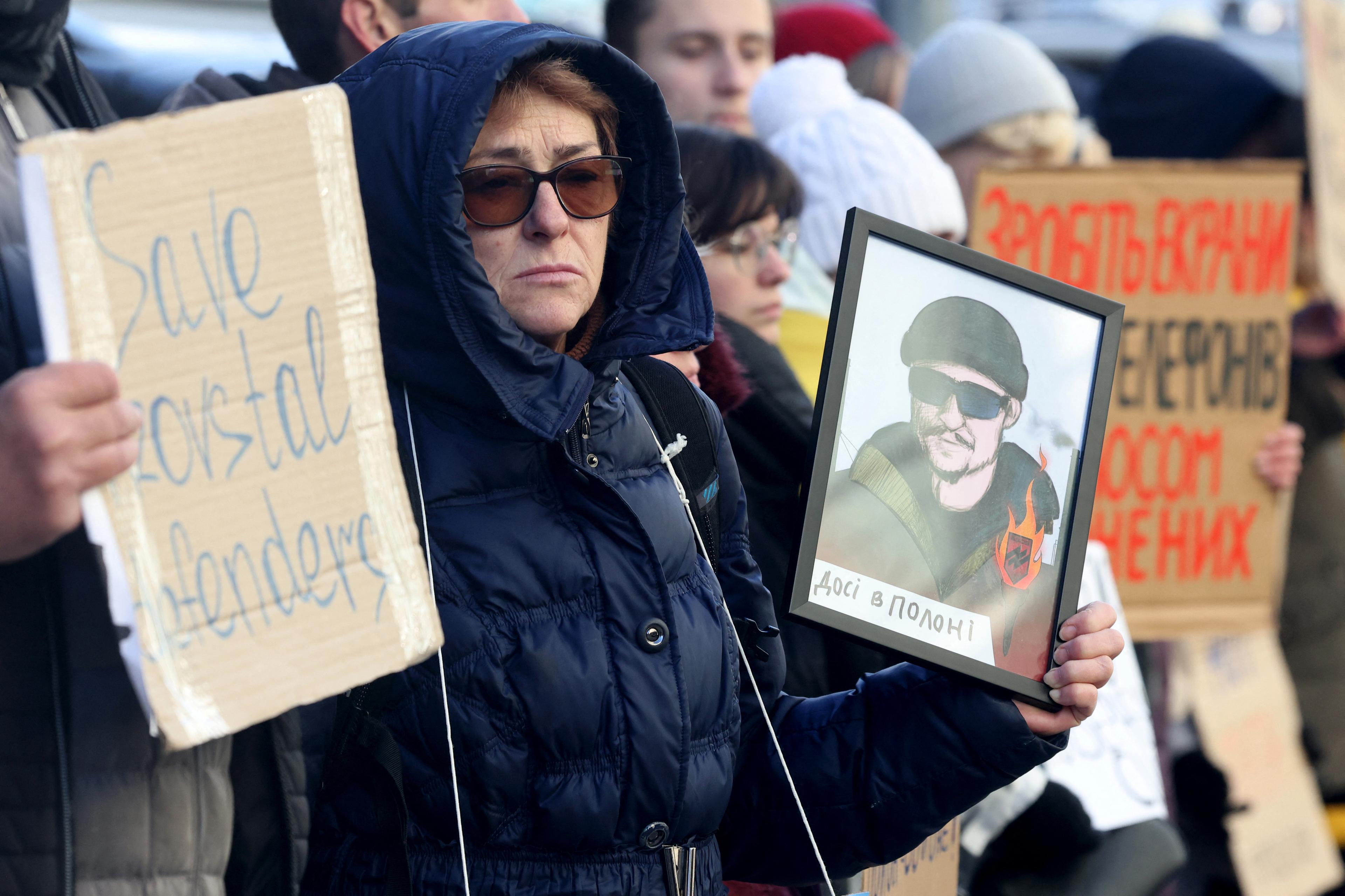 En kvinna håller upp ett porträtt av sin son i samband med ett möte med släktingar och vänner till ukrainska krigsfångar i Kiev den 31 december 2023. Foto: Anatolii Stepanov/AFP via Getty Images