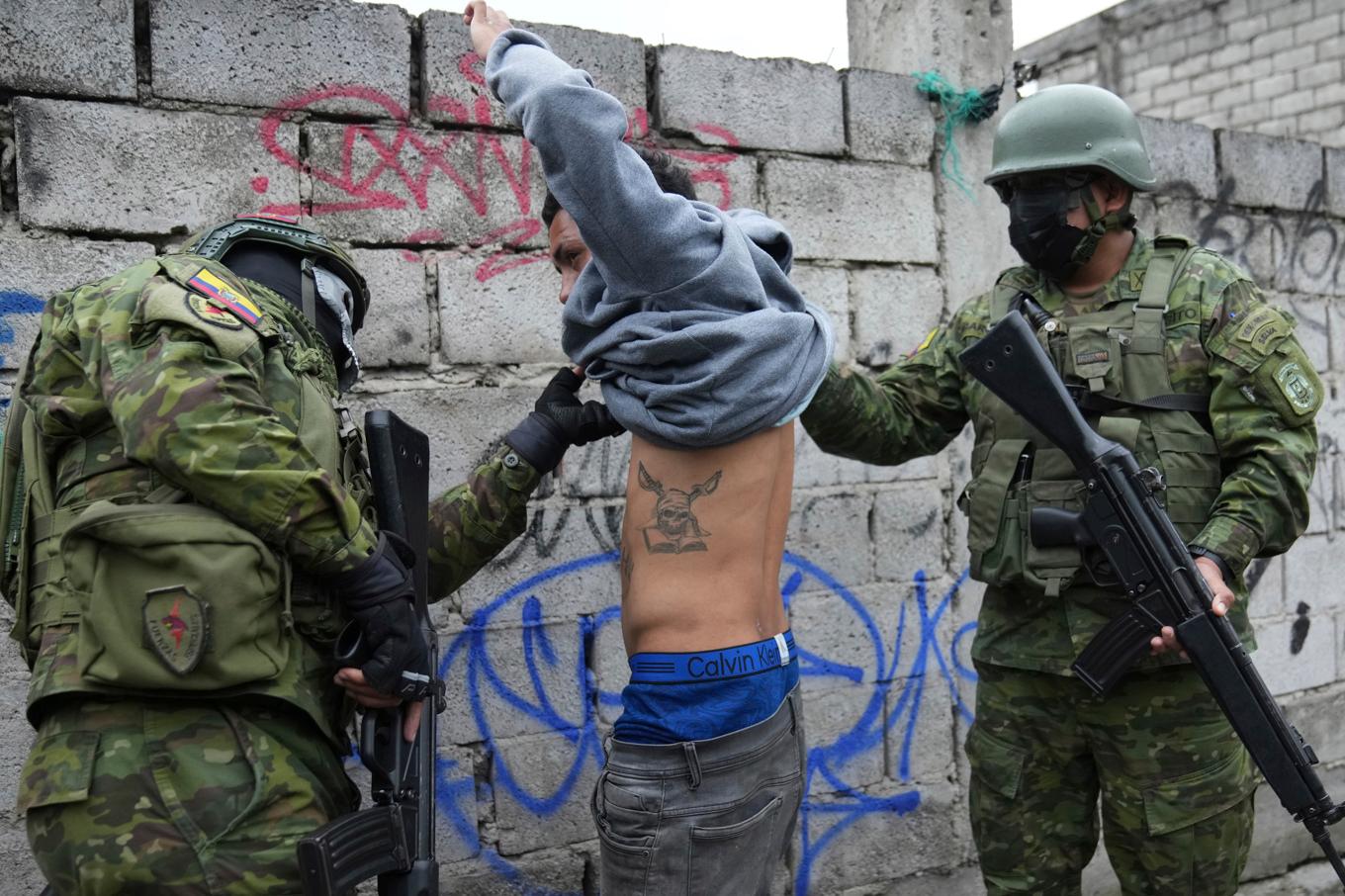 Soldater i den ecuadorianska armén kontrollerar en man på en plats utanför huvudstaden Quito för att se om han har tatueringar som knyter honom till kriminella gäng. Foto: Dolores Ochoa/AP/TT