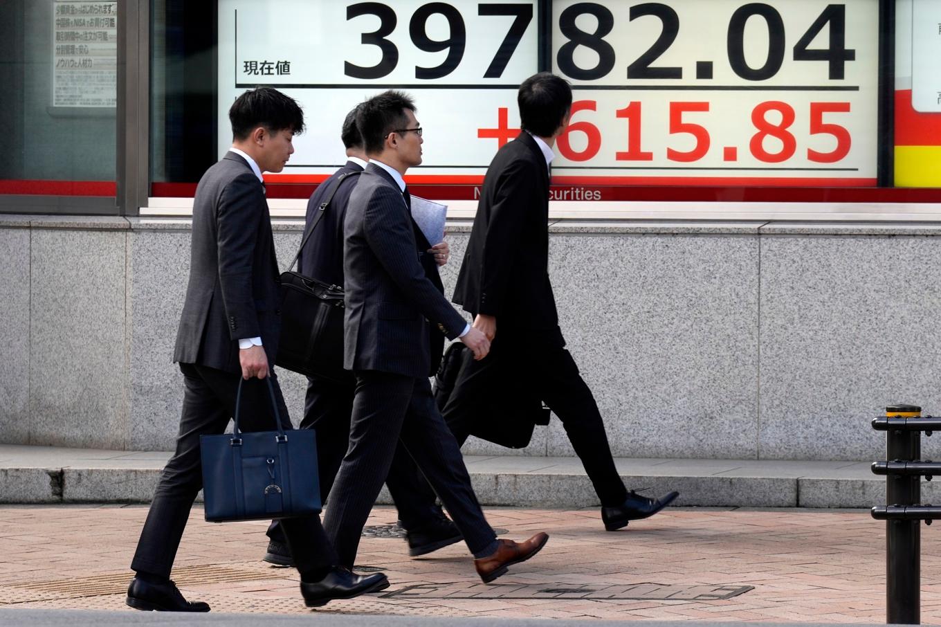 Folk passerar en tavla som visar utvecklingen för Tokyobörsens Nikkei 225-index. Arkivbild. Foto: Eugene Hoshiko/AP/TT