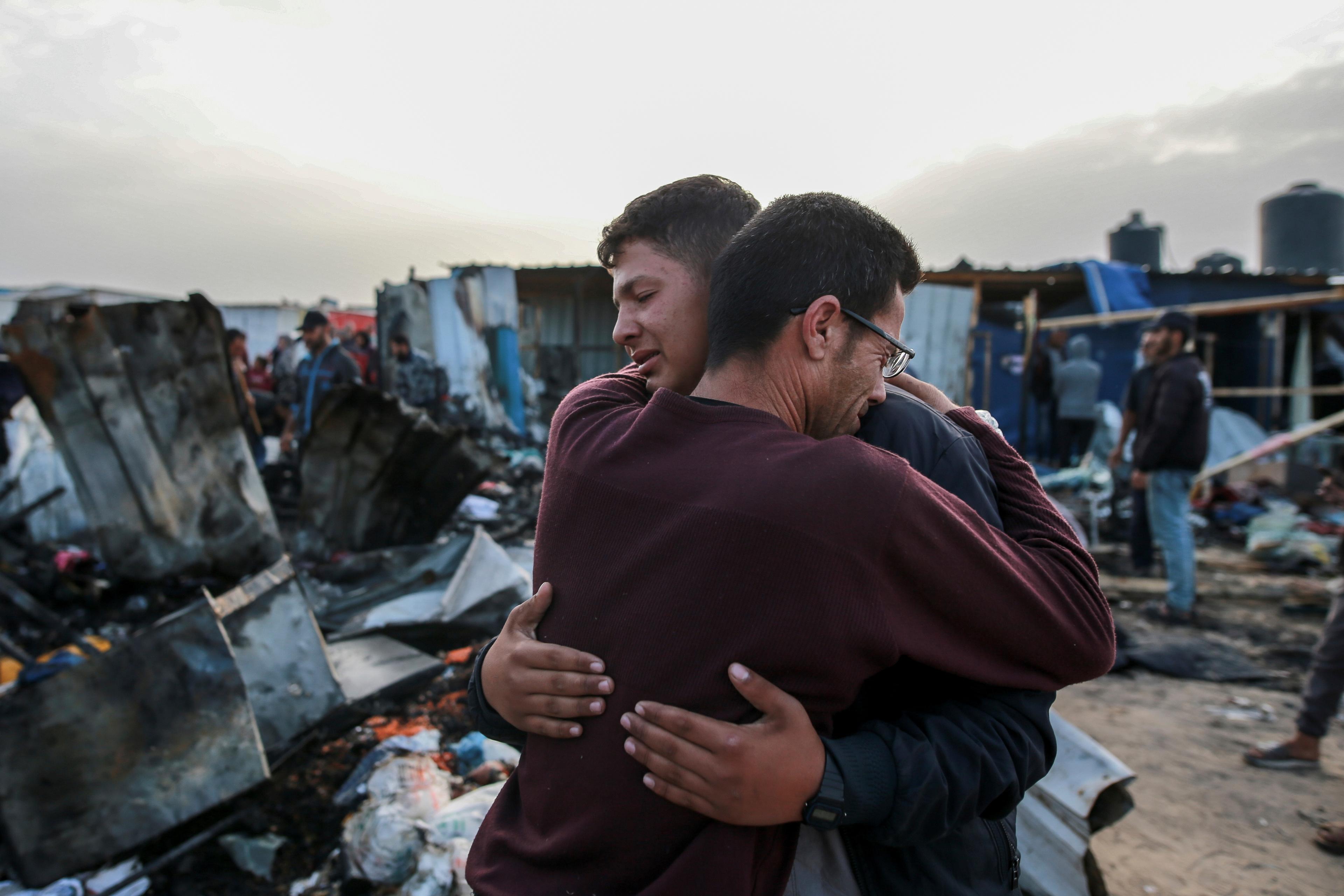 Två män tröstar varandra vid det sönderbombade tältlägret utanför Rafah i Gaza. Foto: Jihad Alshrafi/AP/TT