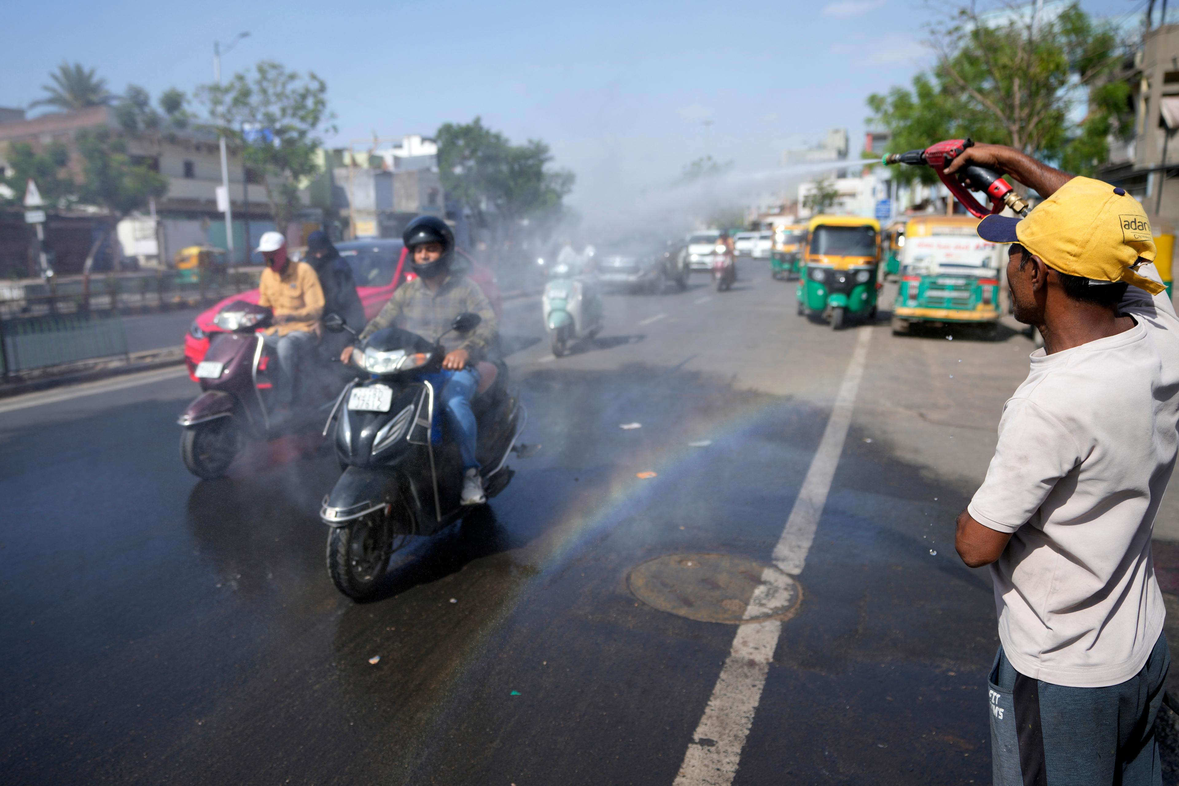 En man som arbetar på en biltvätt i Ahmedabad i delstaten Gujarat svalkar ner förbipasserande trafikanter med vatten. Foto: Ajit Solanki/AP/TT