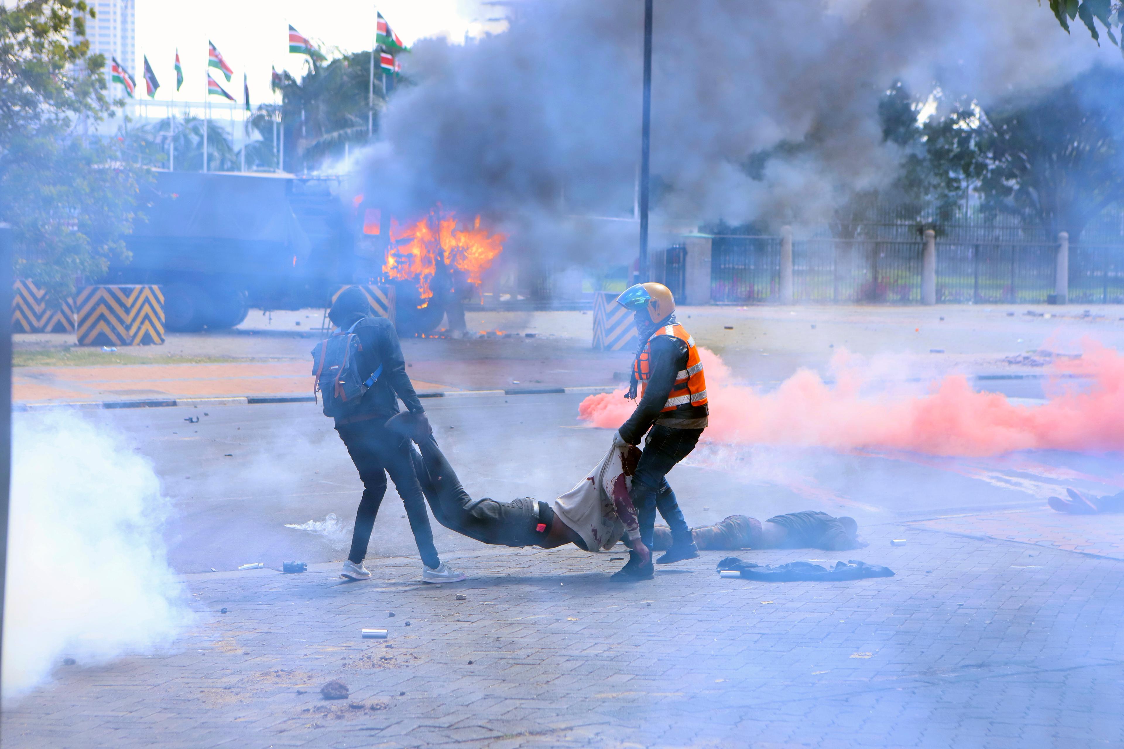 Demonstranter bär bort en man som skadats under tisdagens protester. Foto: Brian Inganga/AP/TT
