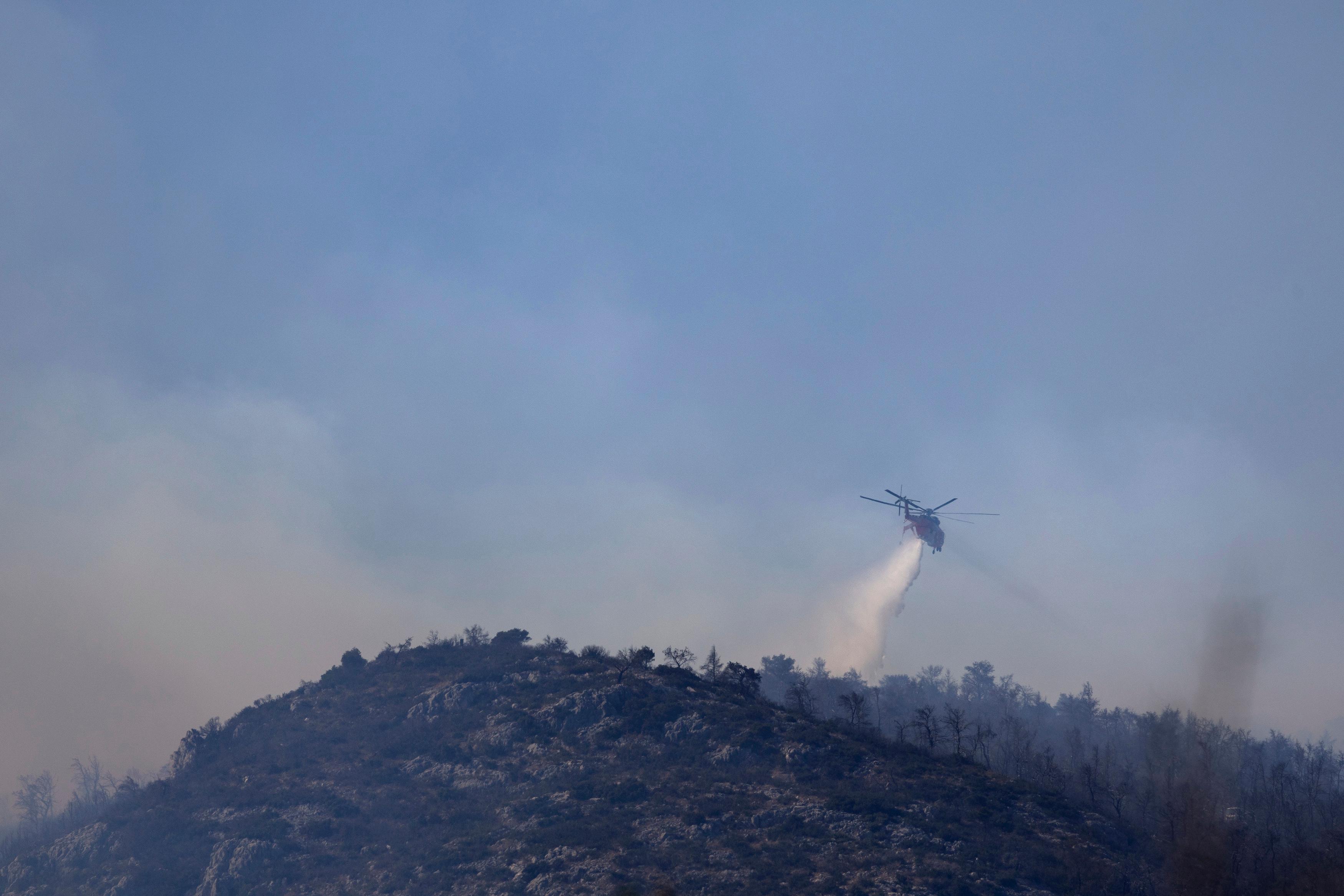 En helikopter som bekämpar en skogsbrand i ett område nordväst om Aten på lördagen. Foto: Yorgos Karahalis/AP/TT
