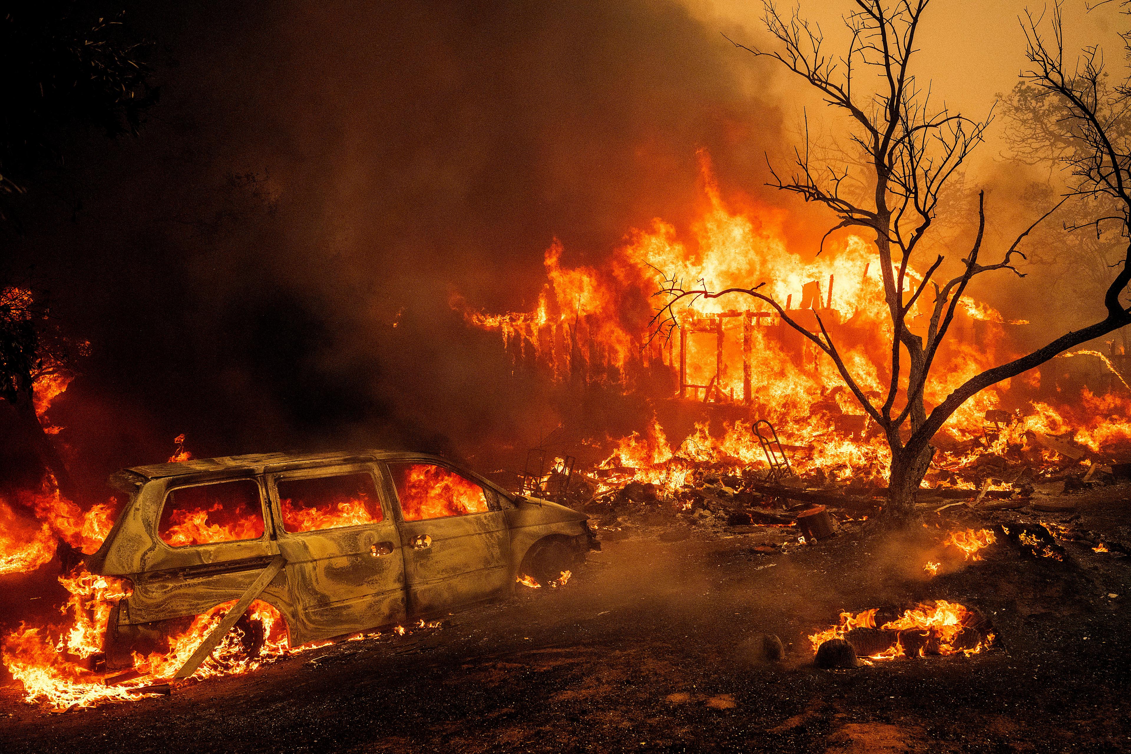 En byggnad och en bil brinner upp i den stora skogsbranden i Oroville. Bild tagen på tisdagen. Foto: Noah Berger/AP/TT