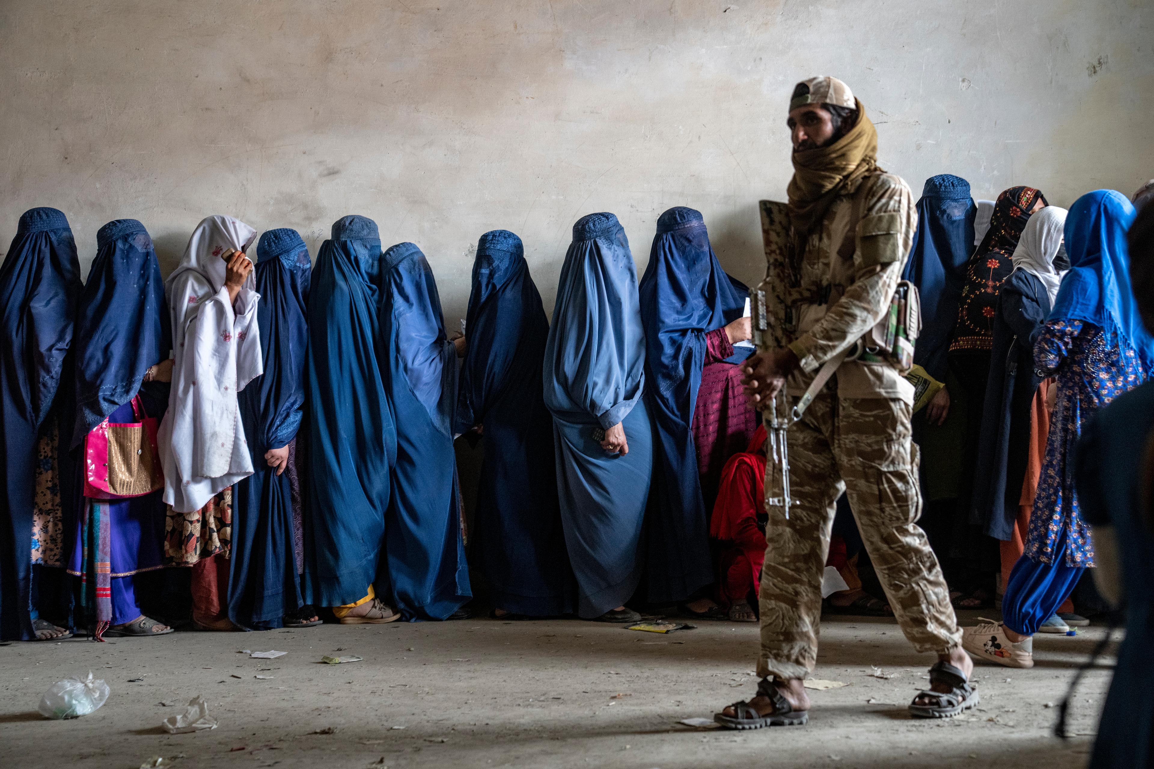 En taliban vaktar kvinnor som köar för hjälpsändningar med mat i Kabul. Arkivbild. Foto: Ebrahim Noroozi/AP/TT