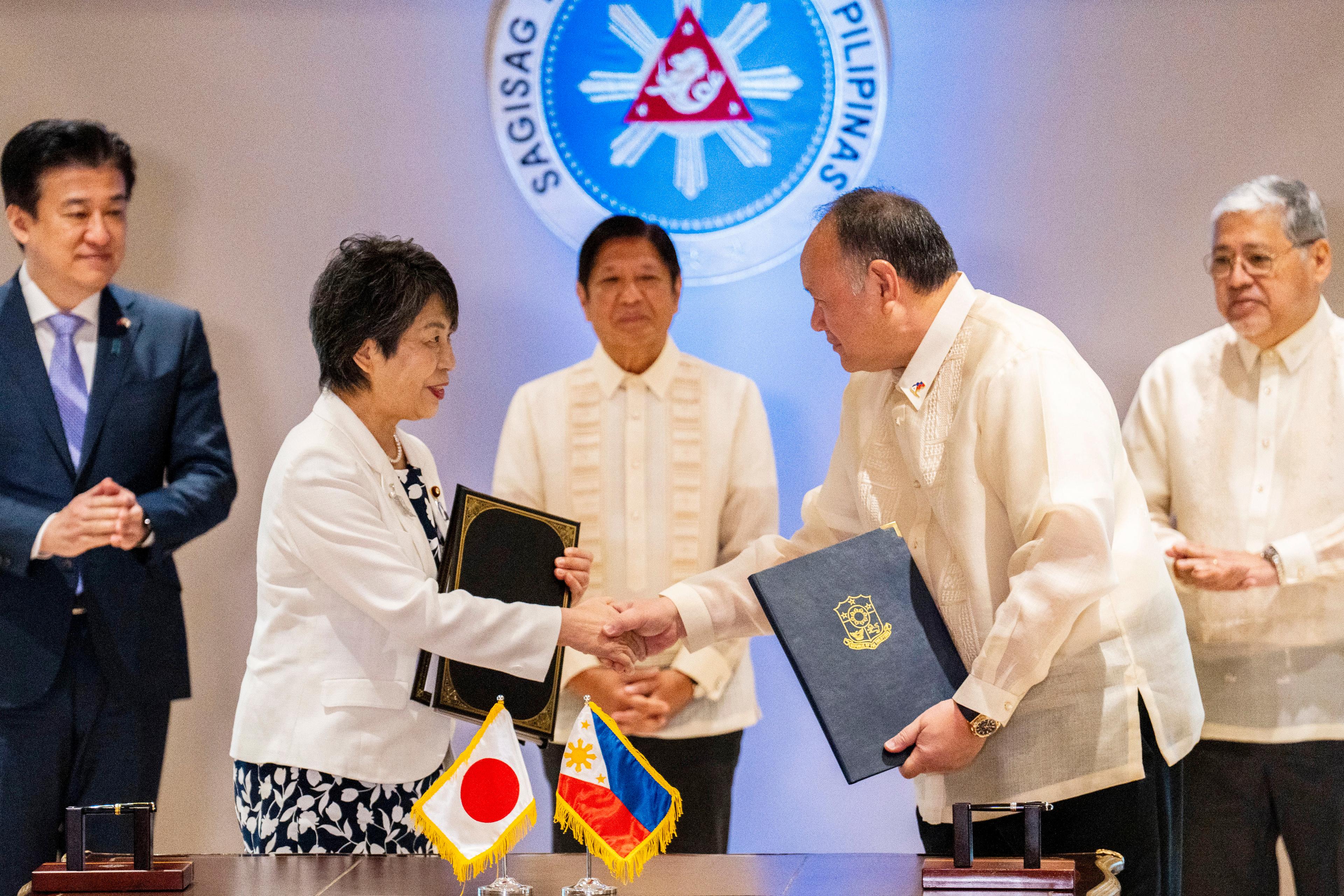 Japans utrikesminister Yoko Kamikawa och Filippinernas försvarsminister Gilberto Teodoro skakar hand efter att ha skrivit under avtalet i Manila på måndagen. Foto: Lisa Marie David/AP/TT