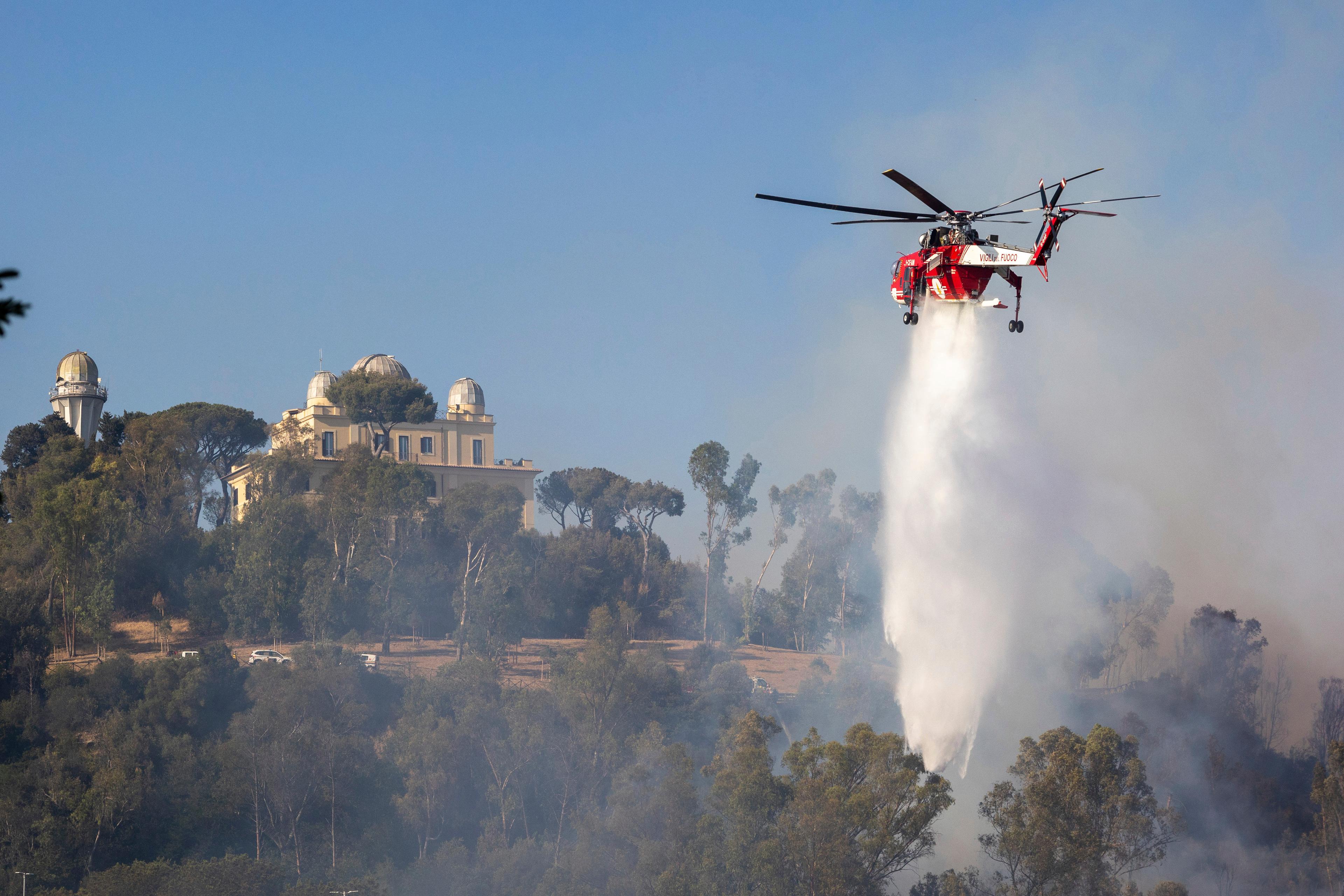 En helikopter vattenbombar branden på Monte Mario i Rom. Foto: Francesco Benvenuti/AP/TT