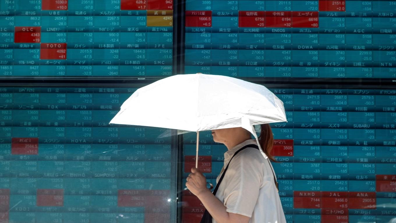 En kvinna går förbi en elektronisk tavla som visar aktiekurserna för Nikkei 255-indexet på Tokyobörsen den 25 juli 2024. Foto: Kazuhiro Nogi/AFP via Getty Images