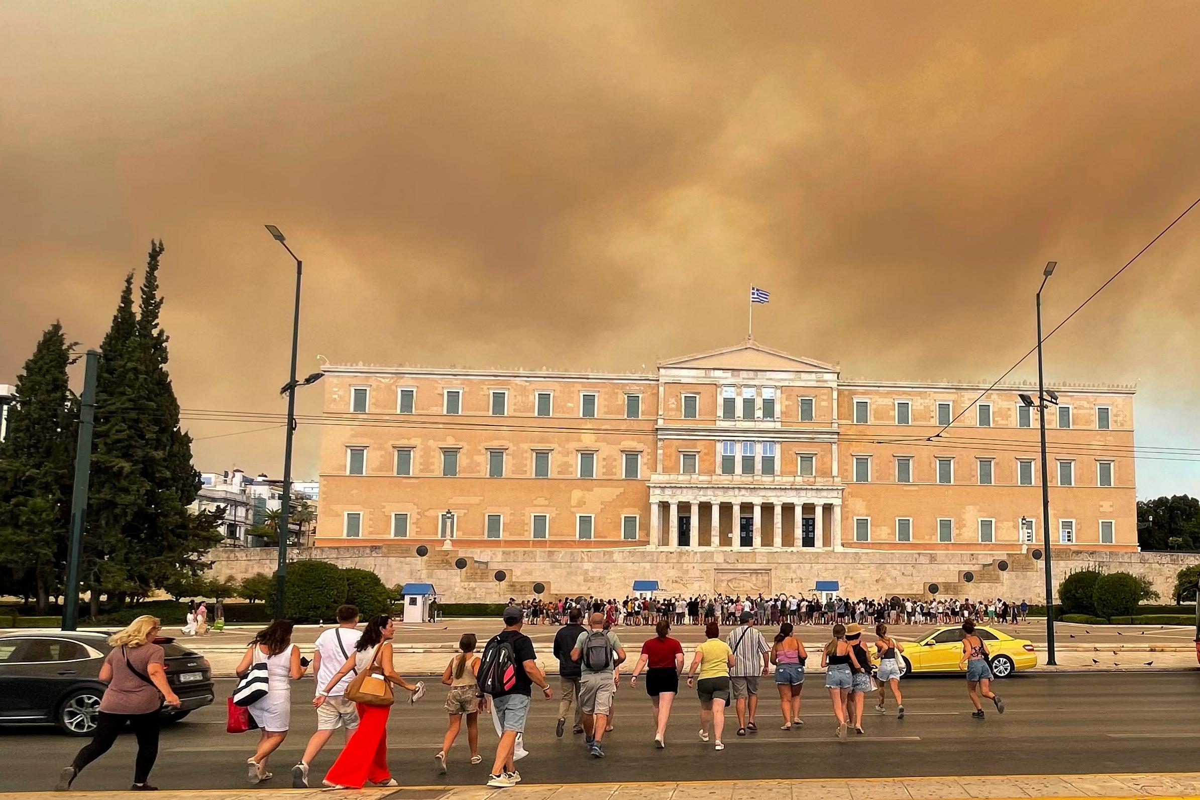 Rök från skogsbränder ses vid parlamentsbyggnaden i Aten. I delar av regionen Attika har invånare evakuerats. Foto: Derek Gatopoulos/AP/TT