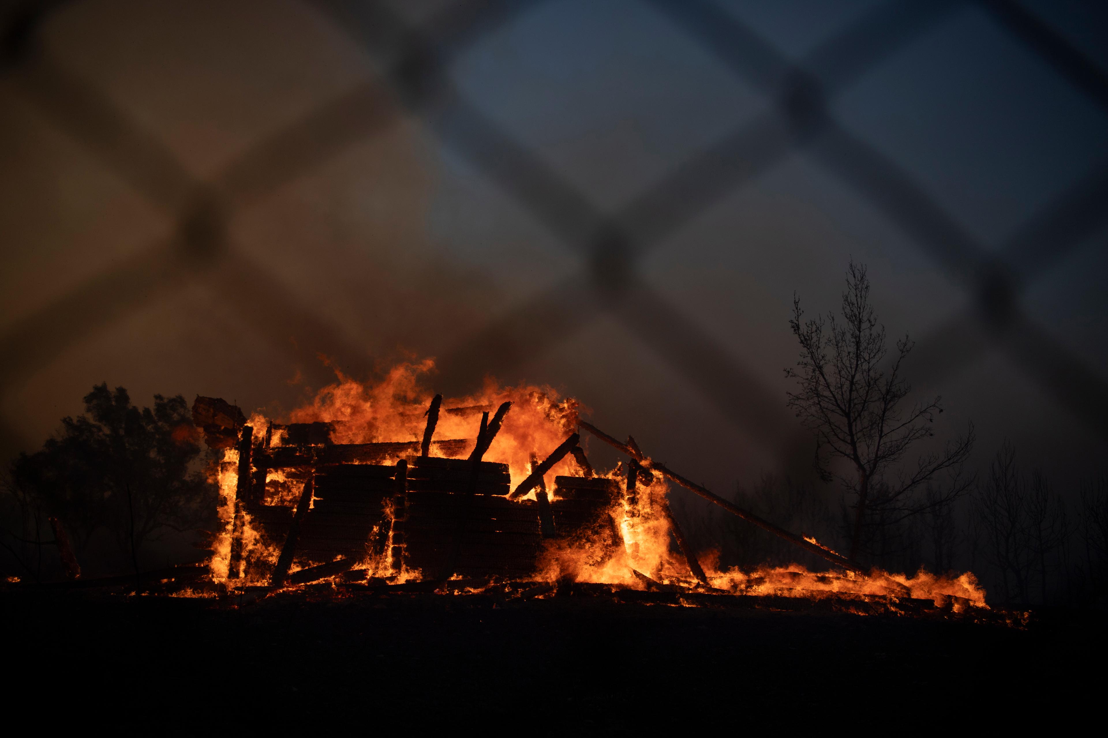 Ett hus norr om Aten brinner till följd av en skogsbrand i området. Foto: Michael Varaklas/AP/TT