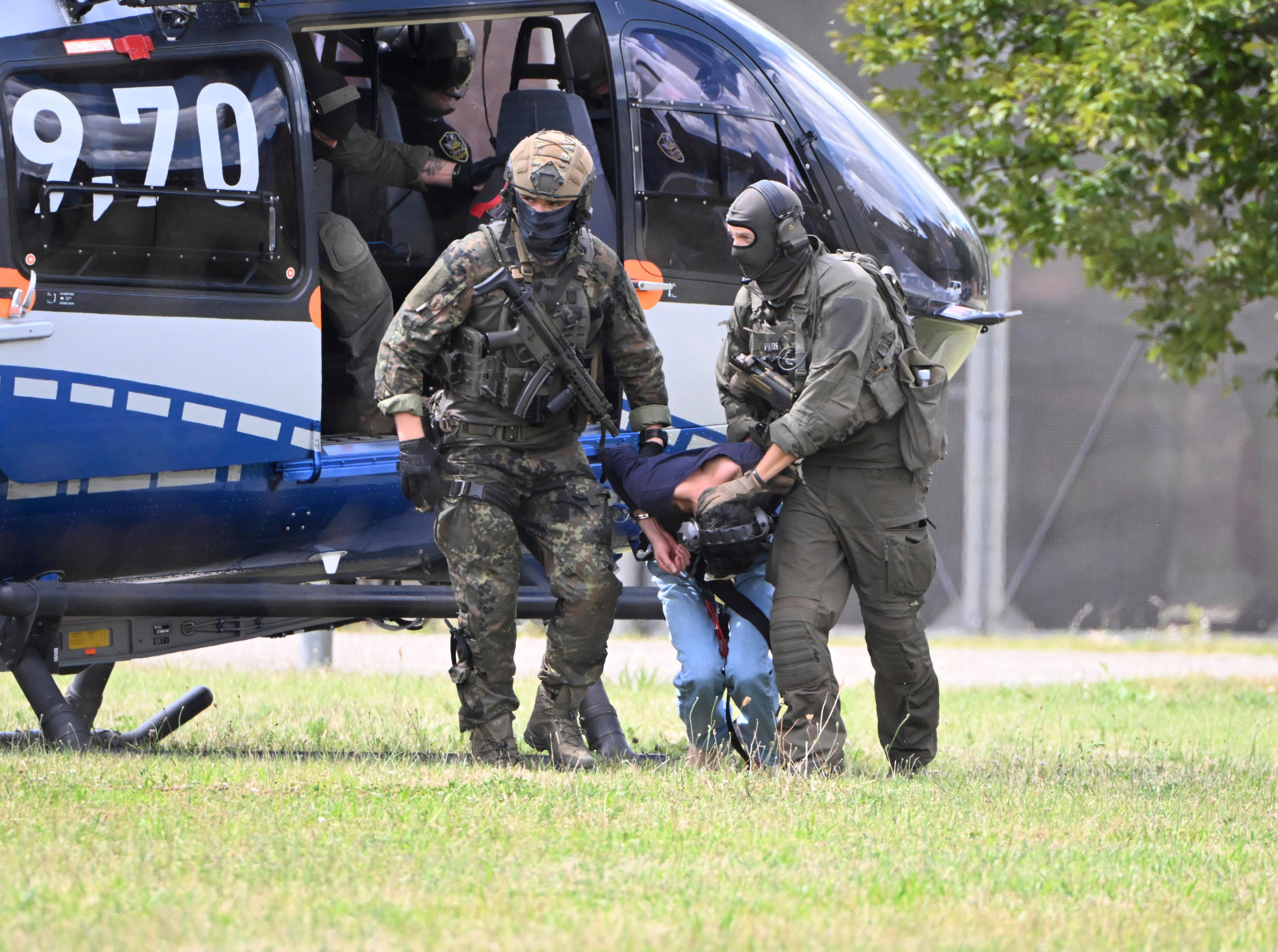 Den misstänkte gärningsmannen i knivattacken i tyska Solingen förs ut från en helikopter av poliser med förstärkningsvapen. Foto: Uli Deck/AP/TT