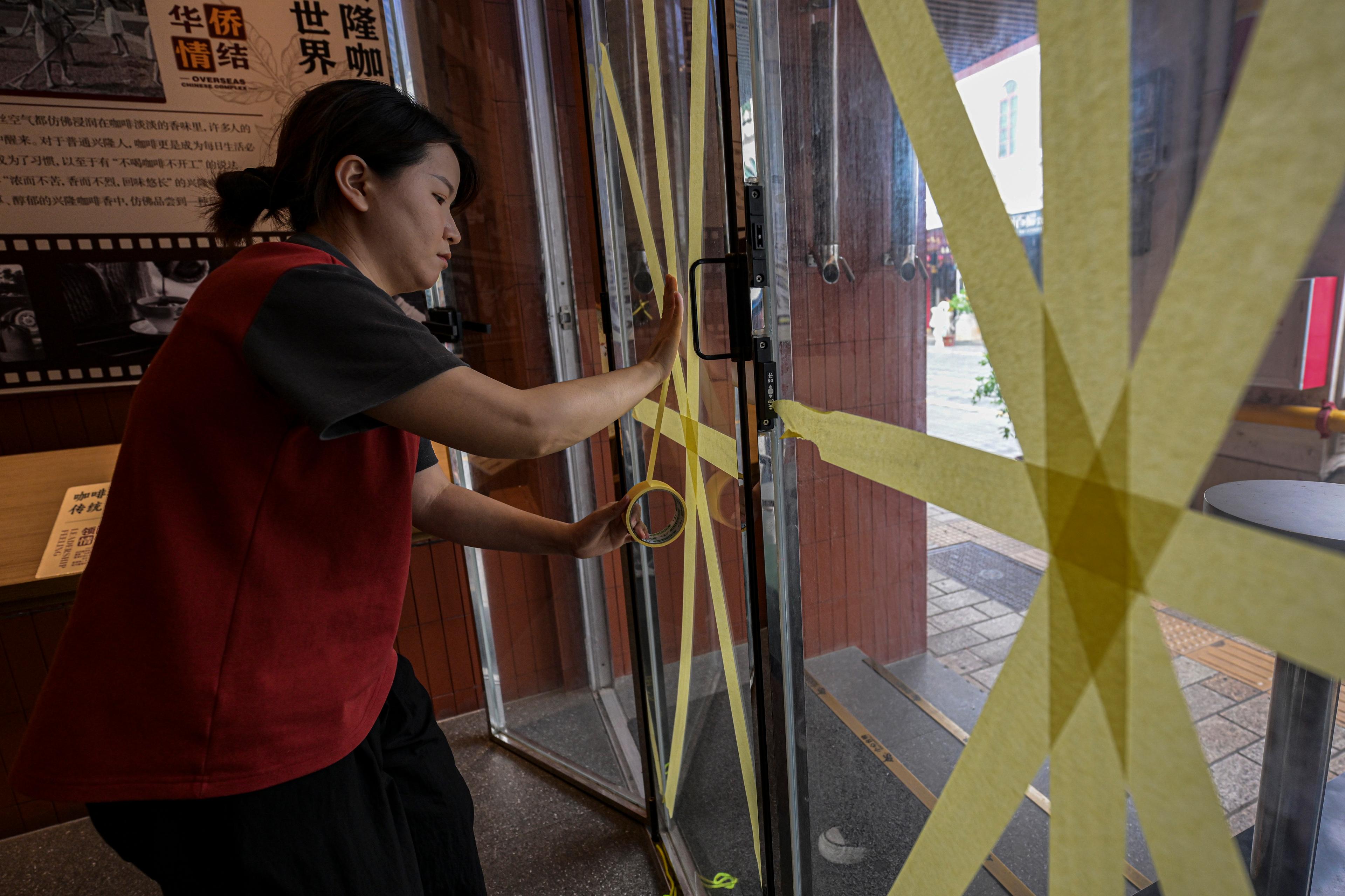 Fönstren på ett kafé i Haikou i provinsen Hainan i södra Kina stärks inför tyfonen Yagis ankomst. Foto: Pu Xiaoxu/AP/TT