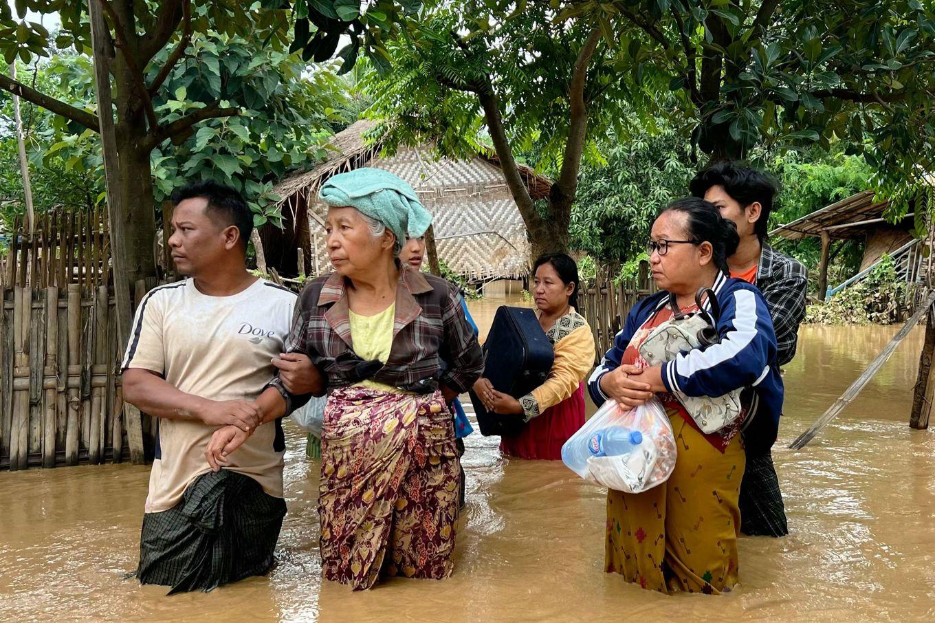 Invånare i en liten by i Naypyidaw-regionen i Myanmar står med sina tillhörigheter i händerna efter de omfattande översvämningarna i landet. Bilden är tagen 13 september. Foto: Sai Aung Main/AFP/TT