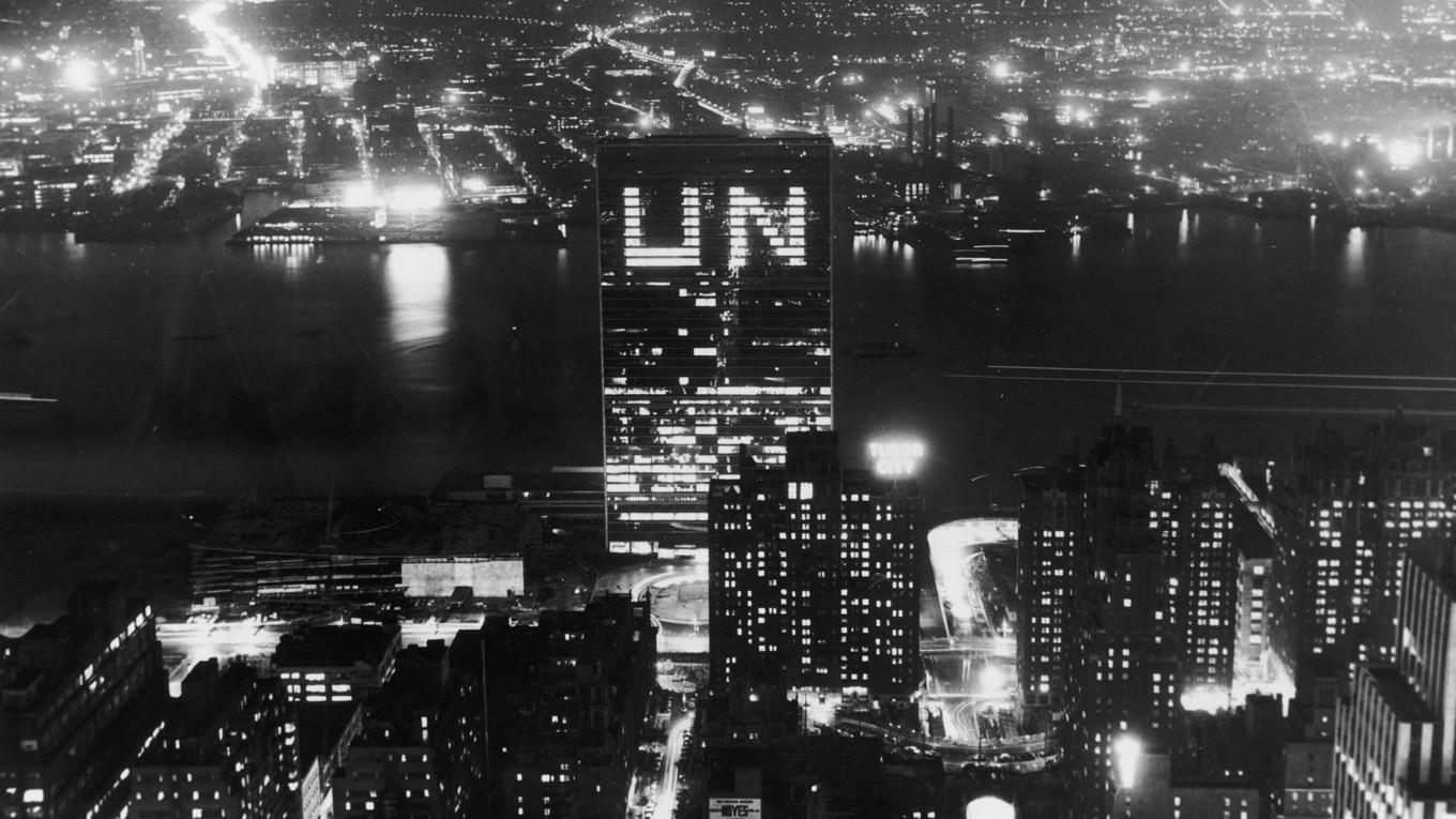 FN-högkvarteret på Manhattan i New York, med East River i bakgrunden. Bilden är från cirka 1955, alltså under den tid som Dag Hammarskjöld var FN:s generalsekreterare.
Generalförsamlingen beslutade under sitt första möte i London 1946 att FN:s högkvarter skulle placeras i USA. Men New York, som det ju sedan kom att bli, var inte ursprungstanken. Philadelphia, San Francisco och Boston var de hetaste kandidaterna för den kommitté som fick i uppdrag att sondera terrängen. När väl New York blev en kandidat var det till en början några platser norr om metropolen som man tittade närmare på. Det som till slut fick kommittén att välja den nuvarande platsen var en gåva på 8,5 miljoner dollar från John D. Rockefeller för inköp av tomten vid First Avenue. Senare utvidgades området genom donationer från staden New York. Från början ville den internationella arkitekt-kommittén, som förestods av Wallace K. Harrison och i vilken de kända arkitekterna Le Corbusier och Oscar Niemeyer ingick, uppföra en byggnad med 45 våningar till en kostnad av 85 miljoner dollar. FN:s förste generalsekreterare, norrmannen Trygve Lie, bantade dock ner notan med 20 miljoner och antalet våningar till 39. Byggandet påbörjades den 24 oktober 1949 och 19 månader senare, den 21 augusti 1951, började man flytta in i byggnaden. USA:s regering gav ett räntefritt lån på 65 miljoner dollar för byggnadskostnaderna. Den sista avbetalningen på lånet gjordes 1982. 
Foto: FPG/Hulton Archive/Getty Images