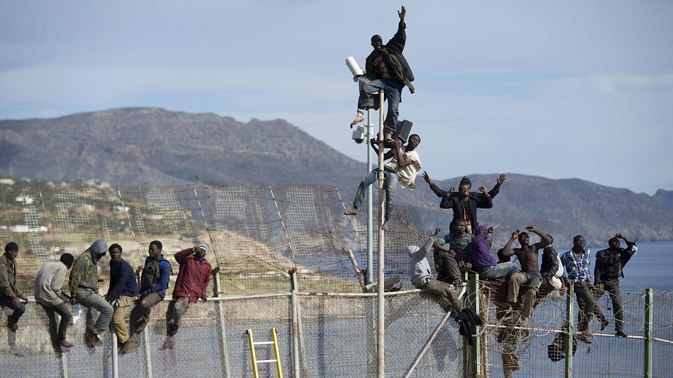 Afrikanska migranter försöker ta sig över stängslet vid gränsen mellan Marocko och den nordafrikanska spanska enklaven Melilla den 3 april 2014. Foto: Alexander Koerner/Getty Images