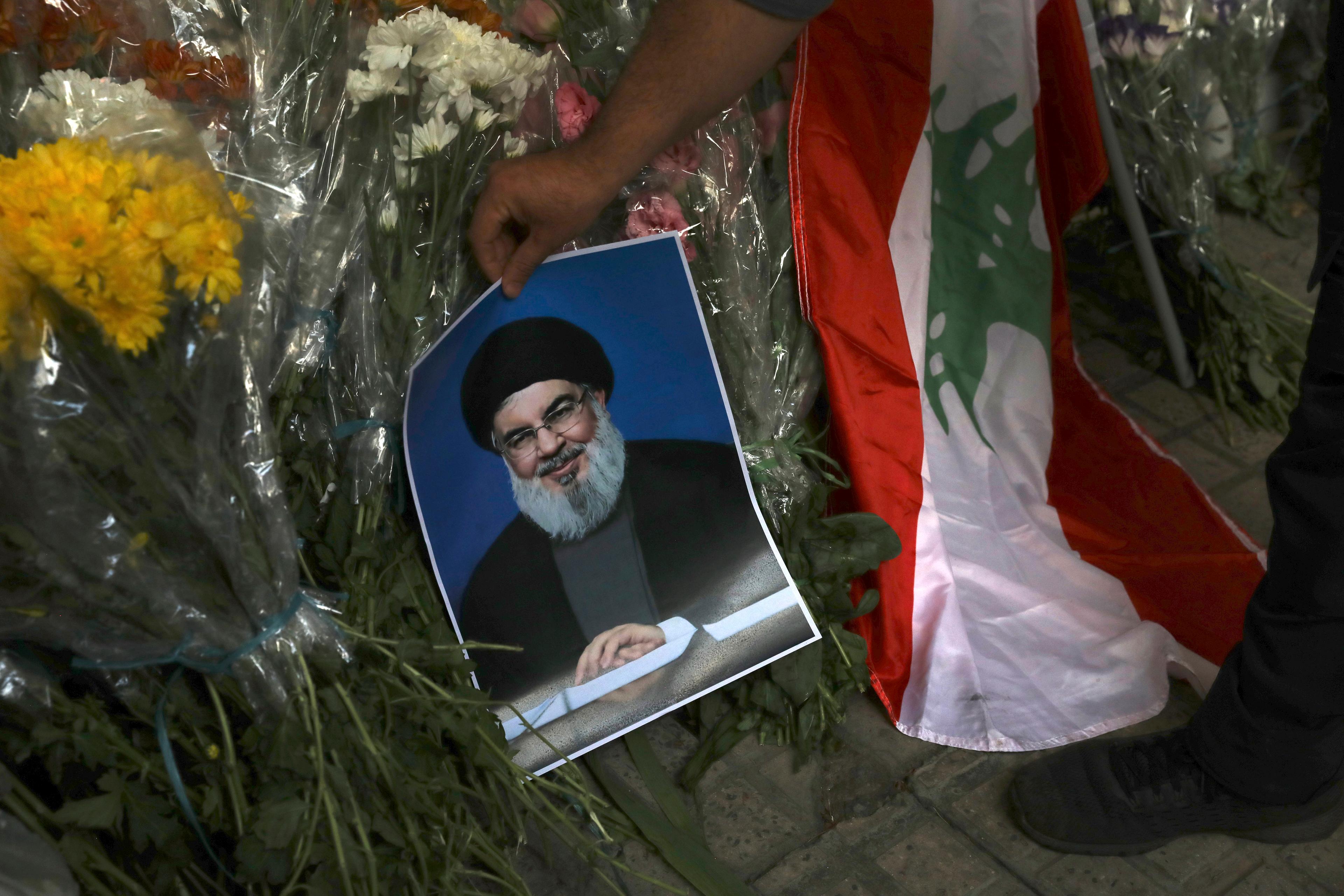 En man placerar en bild på Hizbollahledaren Hassan Nasrallah utanför Libanons ambassad i Teheran på onsdagen. Foto: Vahid Salemi/AP/TT