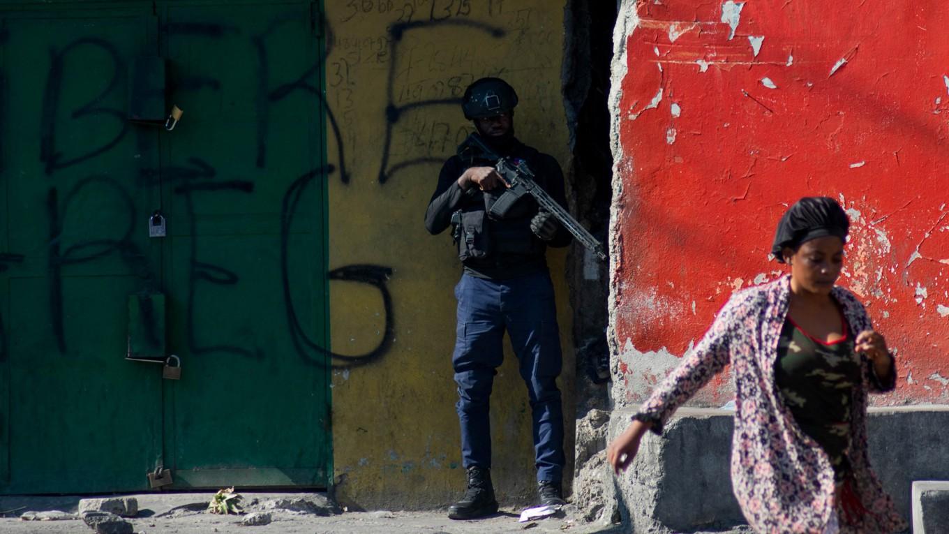 En kvinna går förbi en beväpnad polis som övervakar en gata i Port-au-Prince i Haiti den 22 mars. Foto: Clarens SiffroyAFP via Getty Images