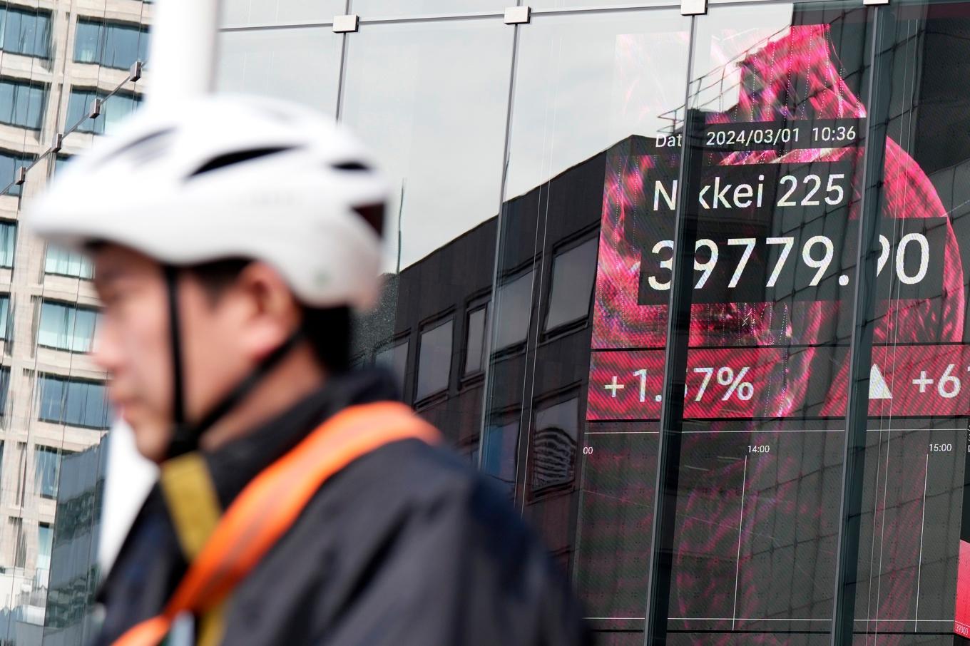 En person framför en skylt som visar börskursen för Nikkei 225. Arkivbild. Foto: Eugene Hoshiko/AP/TT