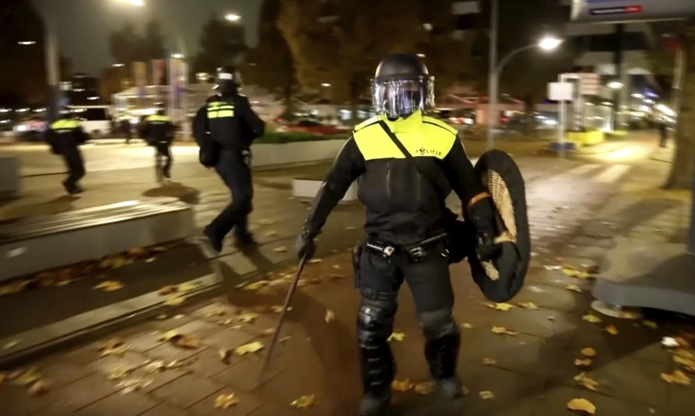 Poliser i kravallutrustning under måndagens protester i Amsterdam. Bilden är tagen från ett videoklipp. Foto: AP/TT