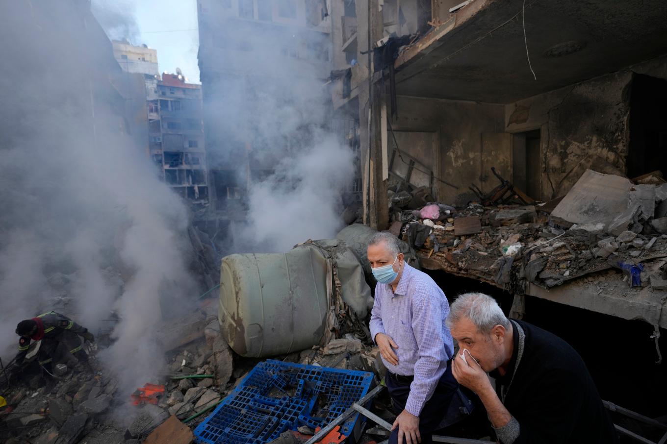 Två män i rasmassorna efter den israeliska attacken mot centrala Beirut. Foto: Hussein Malla/AP/TT