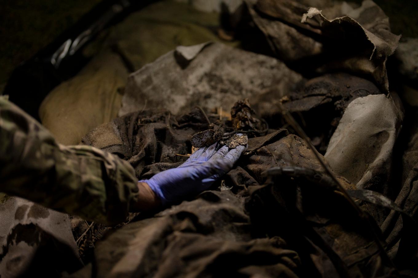 En ukrainsk soldat undersöker kvarlevorna efter en stupad rysk soldat i Slovjansk i östra Ukraina i fjol. Foto: Bram Janssen/AP/TT