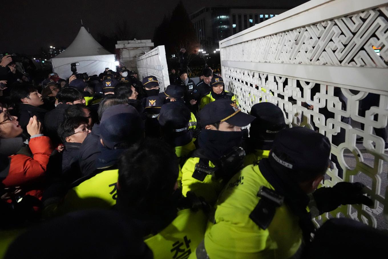 Folksamling försöker ta sig in i parlamentet i Seoul medan polis blockerar byggnaden. Foto: Lee Jin-Man/AP/TT