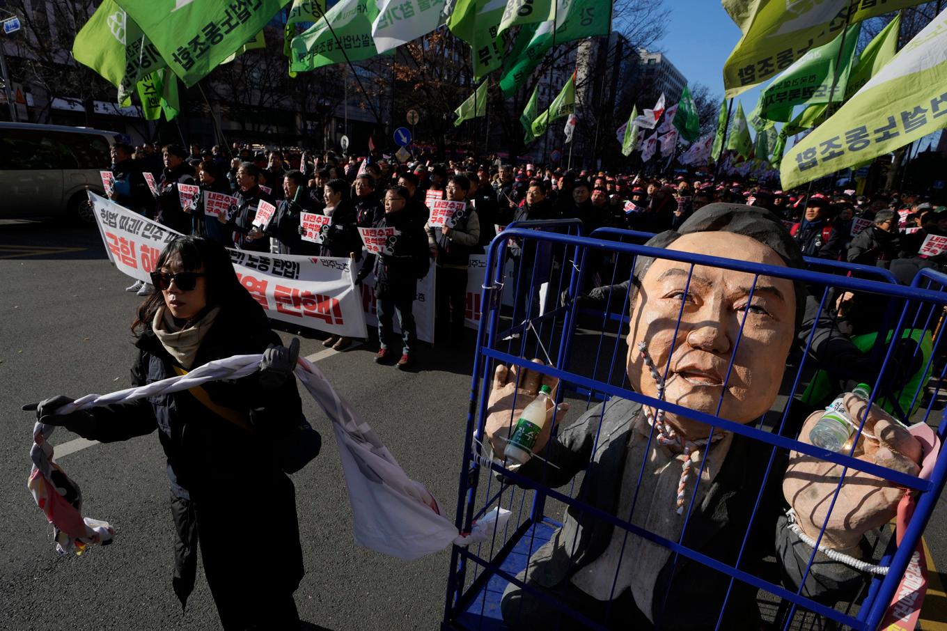 En kvinna drar en docka föreställande Sydkoreas president Yoon Suk-Yeol bakom galler. Bilden togs under de protester mot den kritiserade presidenten som pågår i Seoul. Foto: Ng Han Guan/AP/TT