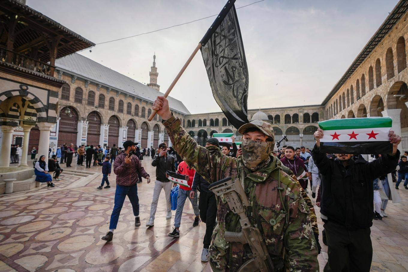 En maskerad man med en HTS-flagga i Damaskus i tisdags. Foto: Hussein Malla/AP/TT