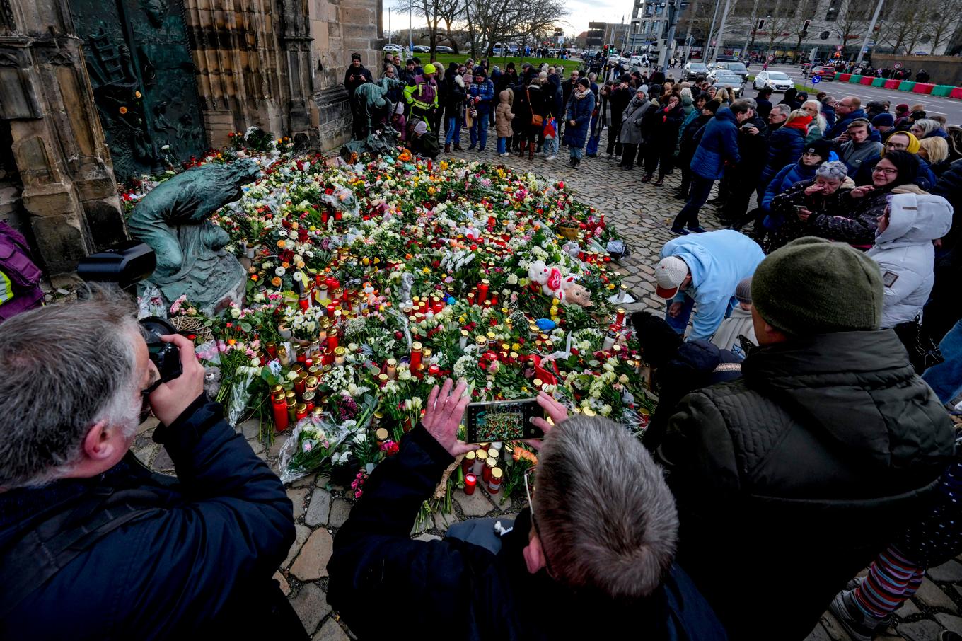 Människor hedrar offren i Magdeburg genom att lägga blommor framför entrén på en kyrka i Magdeburg. Foto: Michael Probst/AP/TT