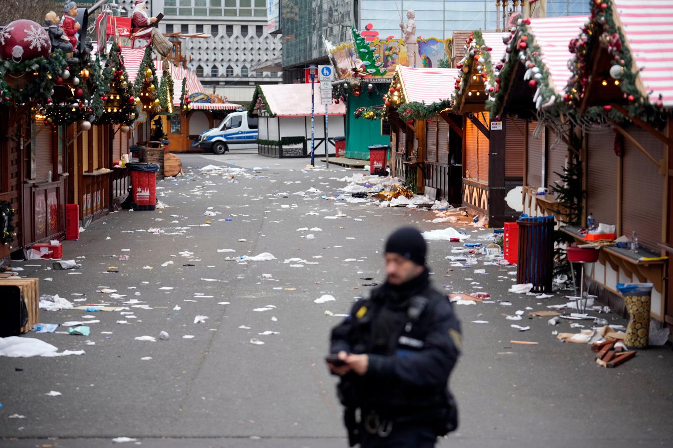 En polis vid den avspärrade julmarknaden i Magdeburg, där flera personer dödades när en bil körde in i en folkmassa på lördagen. Foto: Ebrahim Noroozi/AP/TT