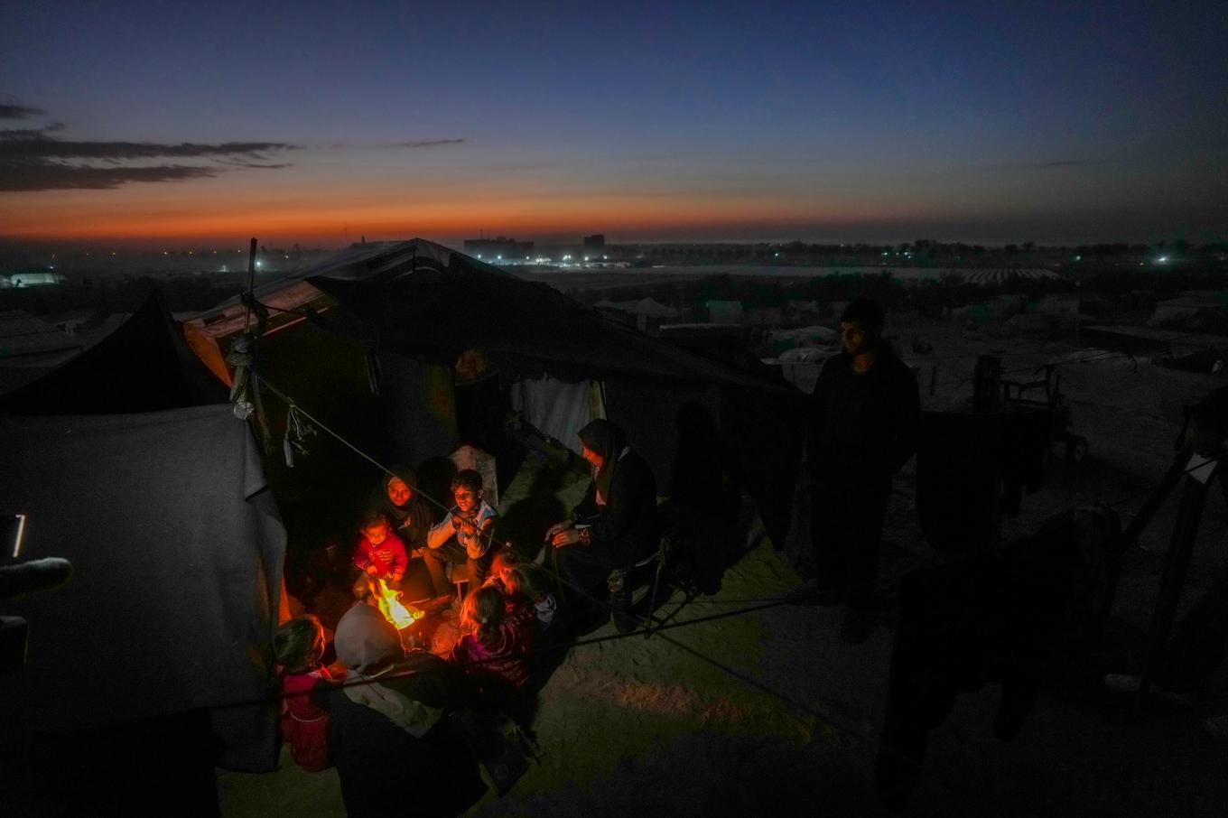 Reda Abu Zarada, 50, har flytt från Jabalia i norra Gaza, sitter vid en brasa med sina barnbarn i ett läger vid havet i Khan Younis, Gaza. Foto: Abdel Kareem Hana/AP/TT