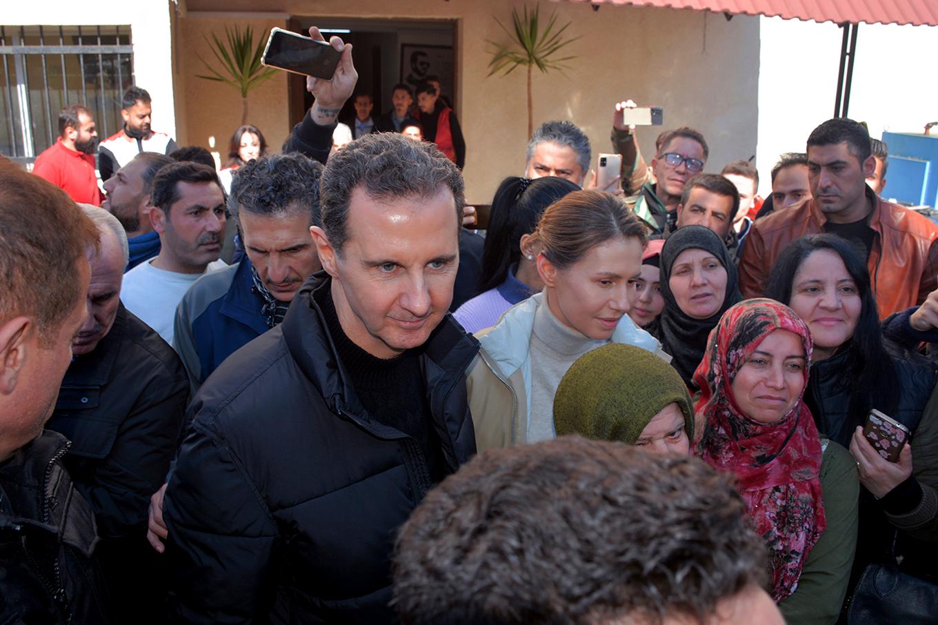 Bashar och Asma al-Assad, i mitten, vid ett besök i ett jordbävningsdrabbat område i västra Syrien förra året. Foto: Sana via AP/TT