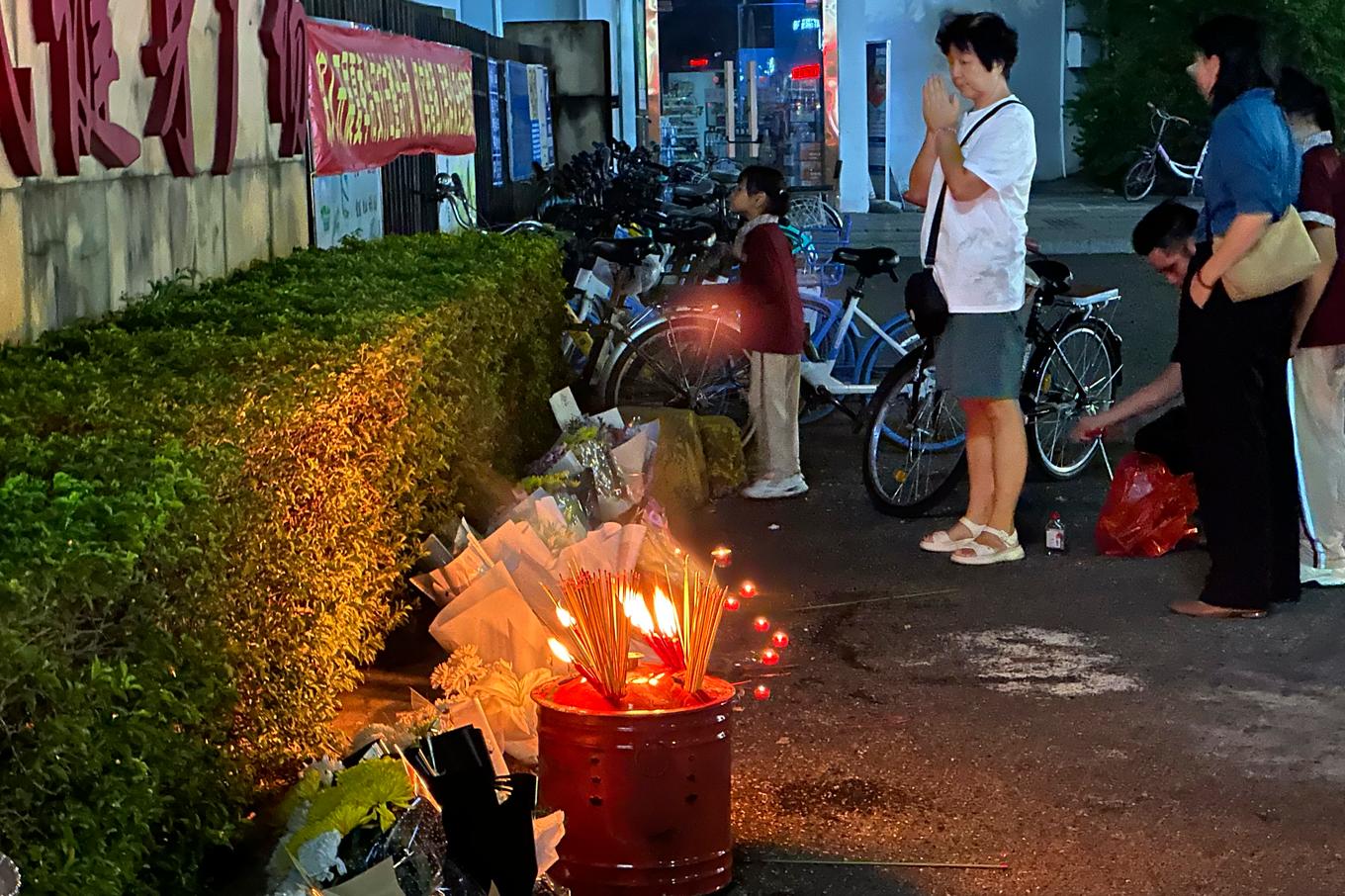 En kvinna hedrar offren med rökelse och blommor utanför sportarenan där attacken inträffade. Bild från november 2024. Foto: Ng Han Guan/AP/TT