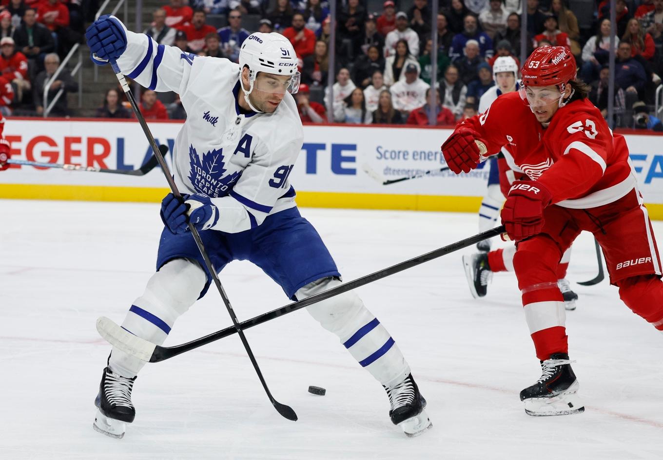 Torontos center John Tavares, t v, passar pucken bakåt mellan benen medan Detroitbacken Moritz Seider bara kan se på. Detroit förlorade, trots tränarbyte, med 2–5. Foto: Duane Burleson/AP/TT