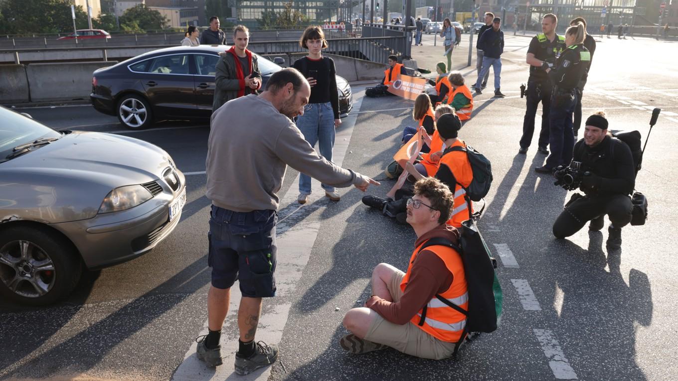 En bilist argumenterar med personer från klimataktivistgruppen ”Last Generation” (Letzte Generation) som blockerar en korsning vid en avfart från motorvägen A100 den 28 september 2023 i Berlin i Tyskland. Foto: Sean Gallup/Getty Images