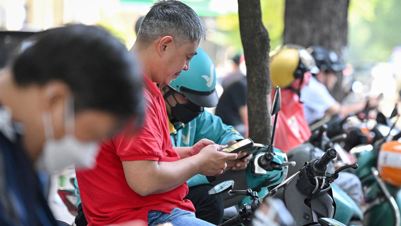 Män använder sina smartphones i Vietnams huvudstad Ho Chi Minh. Bilden är tagen den 24 december i år. Foto: Nhac Nguyen/AFP via Getty Images