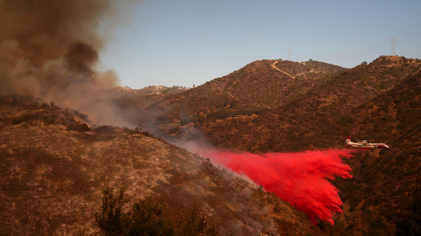 Ett flygplan släpper brandskyddsmedel över en Palisadesbranden i Los Angeles under lördagen. Foto: Eric Thayer/AP/TT